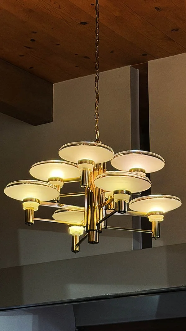 Brass chandelier with two tiers of disc-shaped shades hanging from a wood ceiling at Elmer's Restaurant in Palm Springs