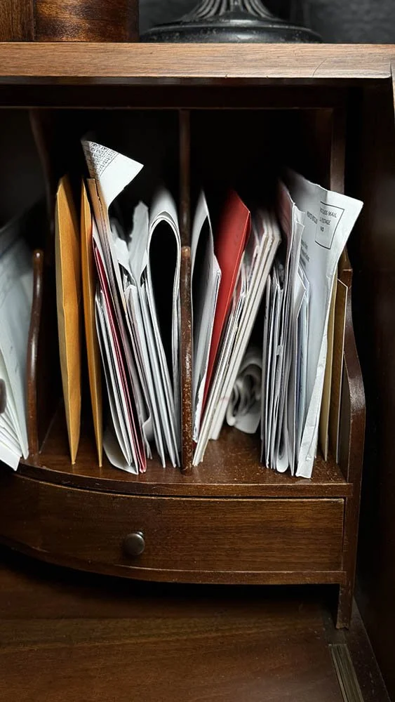 Pigeonhole storage compartments inside an antique secretary desk, filled with papers and envelopes.