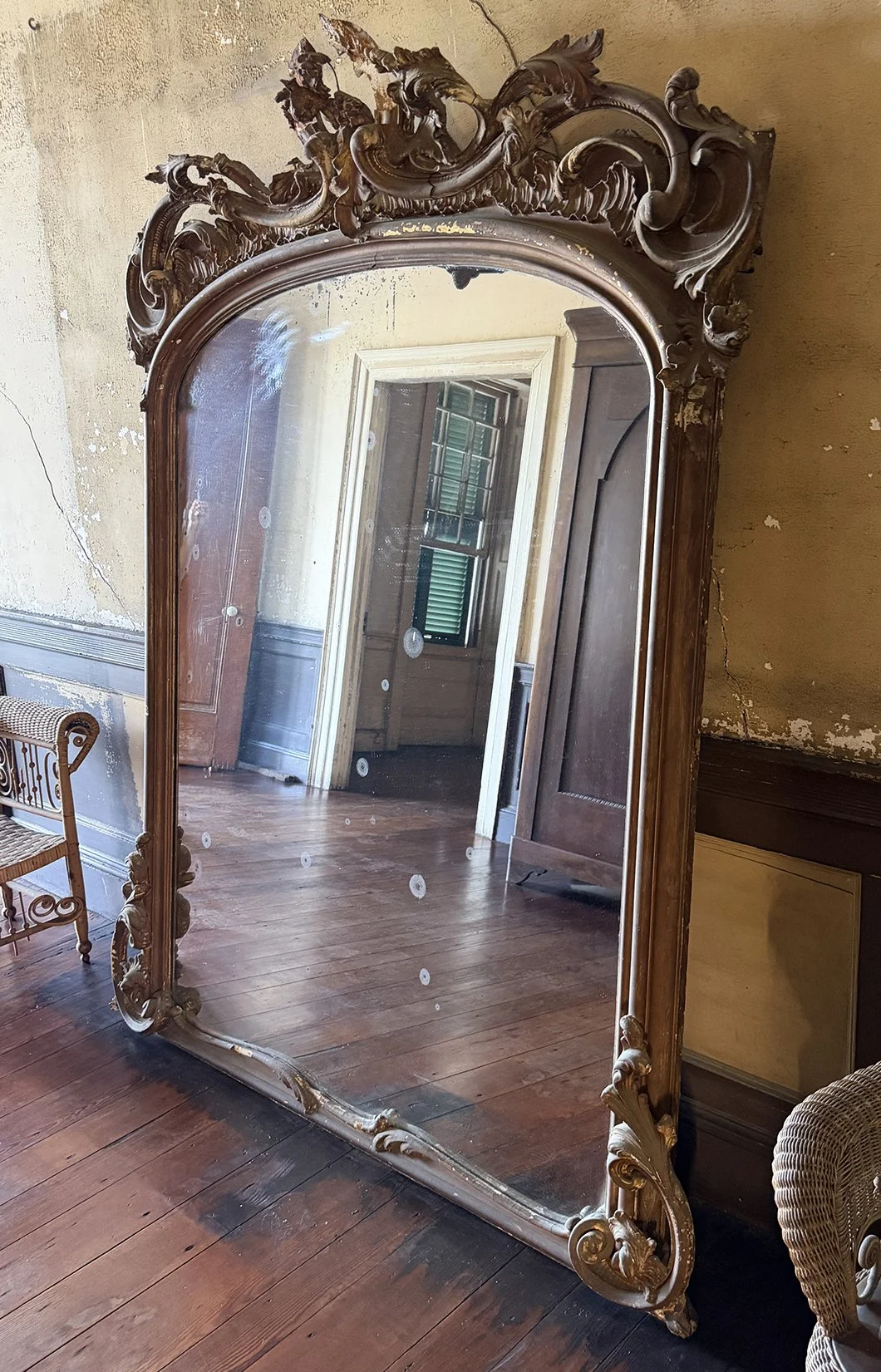 Antique rococo mirror in carved gilt wood against aged plaster walls at the Aiken-Rhett House in Charleston