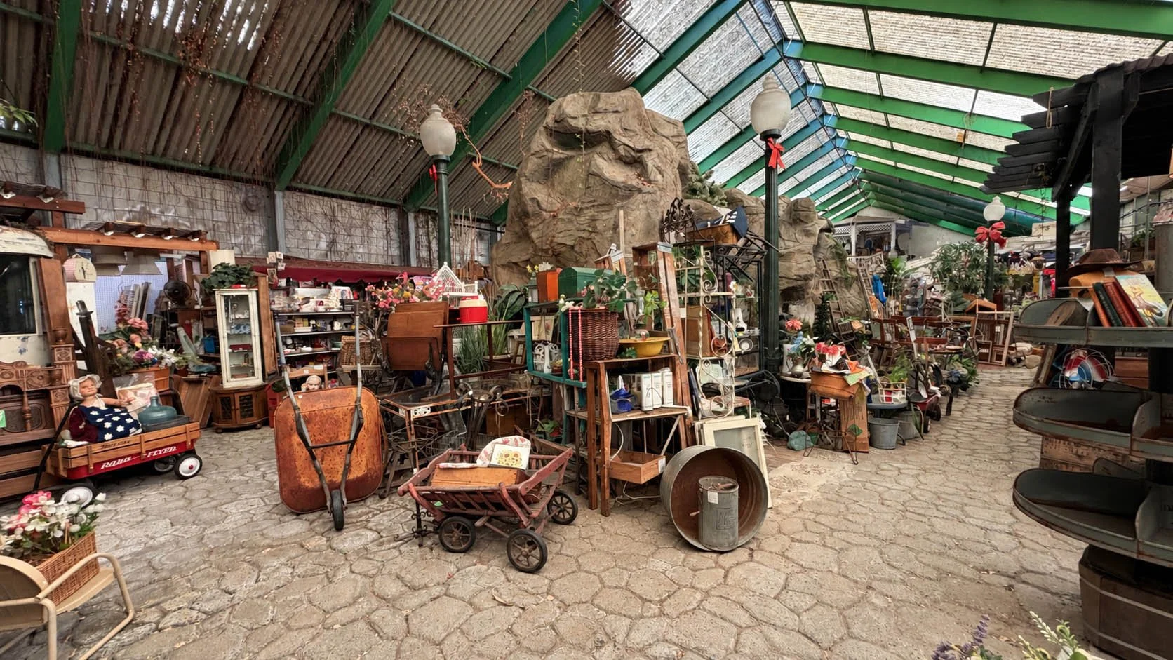 Inside Gum's Mall of Antiques, with a greenhouse roof, rock waterfall, and aisles of vintage furniture