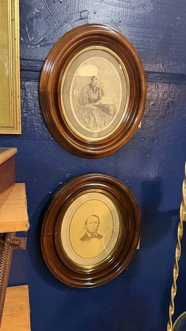 Dark wood oval frames styled with vintage portrait photographs on a navy wall