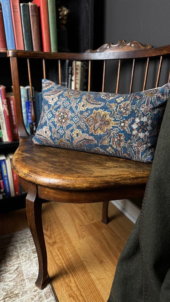 Antique Windsor chair with a kilim pillow in a dark academia home library corner