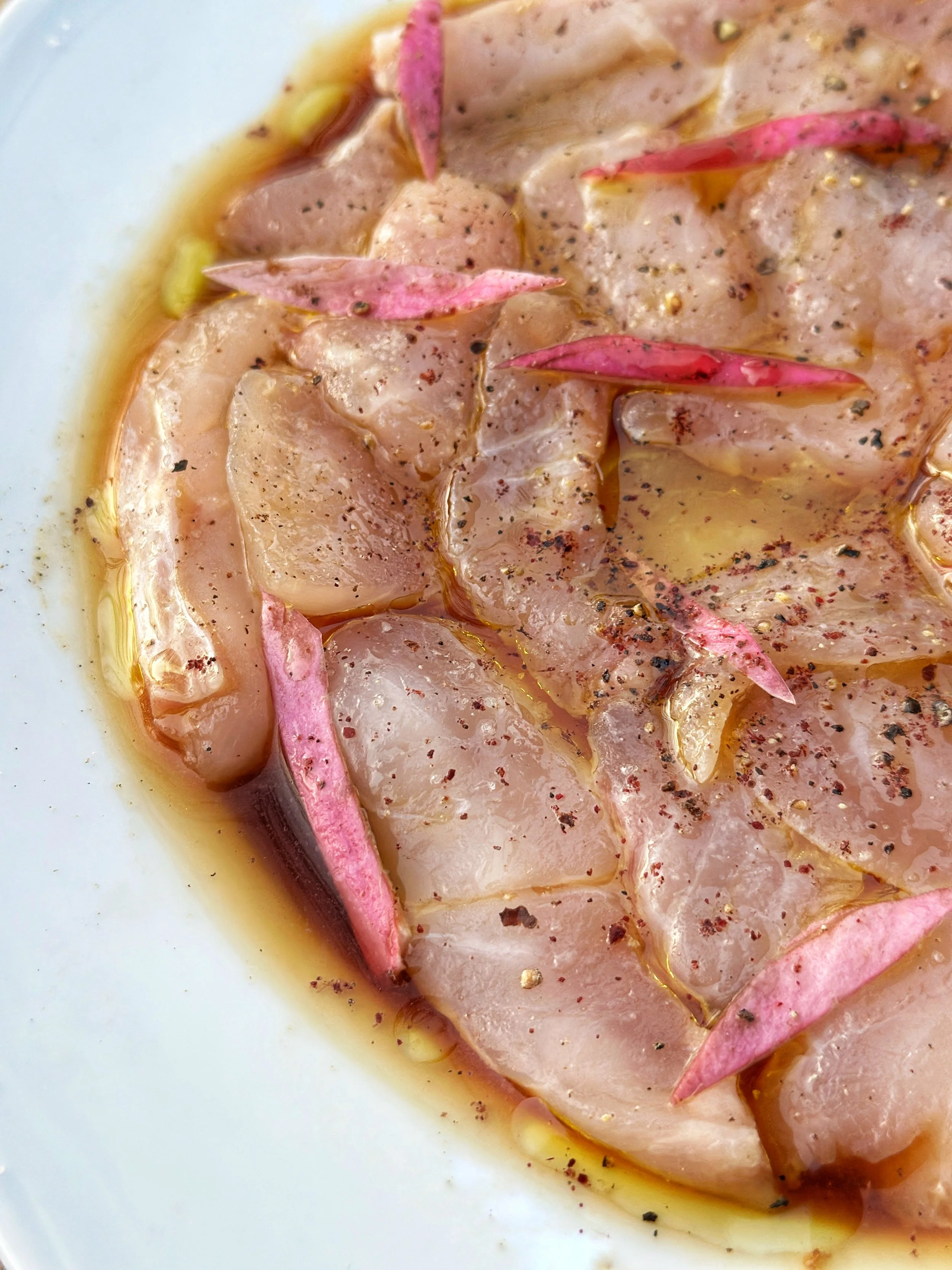 Carpaccio de poisson blanc, magnolia et une sauce à l'huile et aux épices.