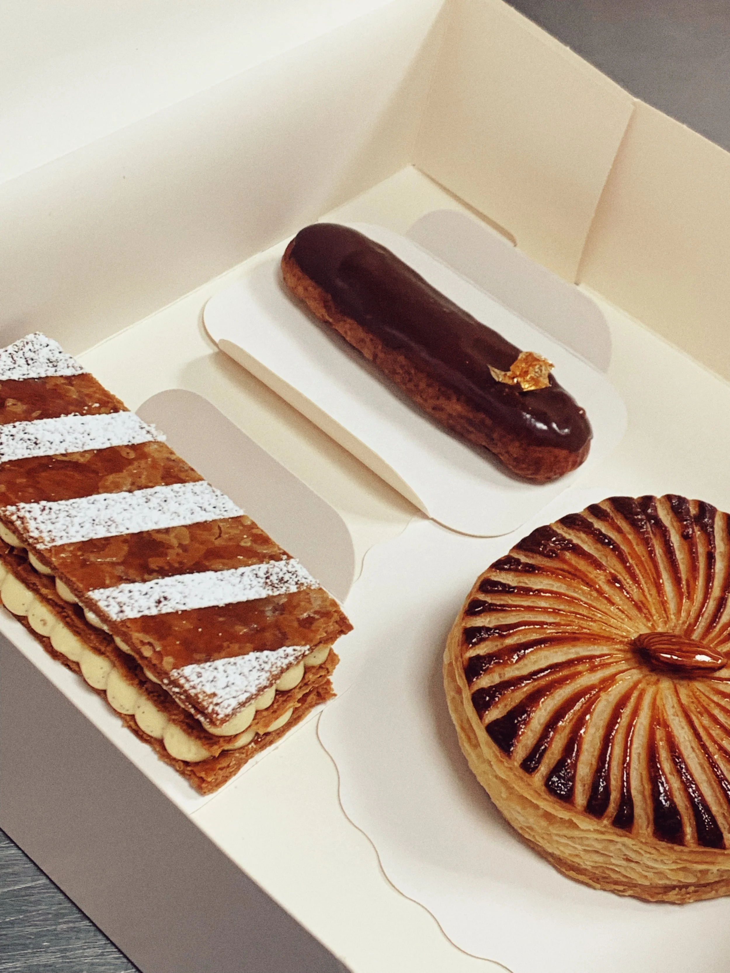 Mini galette des rois brillante, un millefeuilles à la vanille, et un éclair au chocolat.