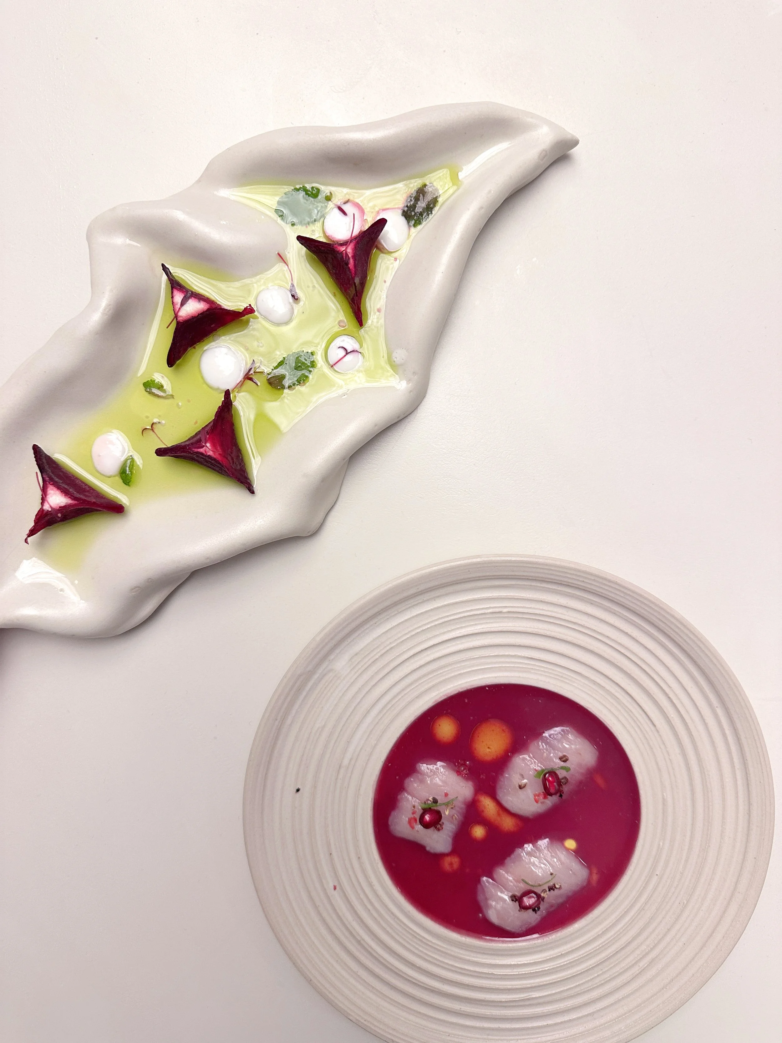 Plateaux d'amuse bouche, ravioles de betterave dans une huile verte et sashimi de poisson blanc dans une sauce à la grenade