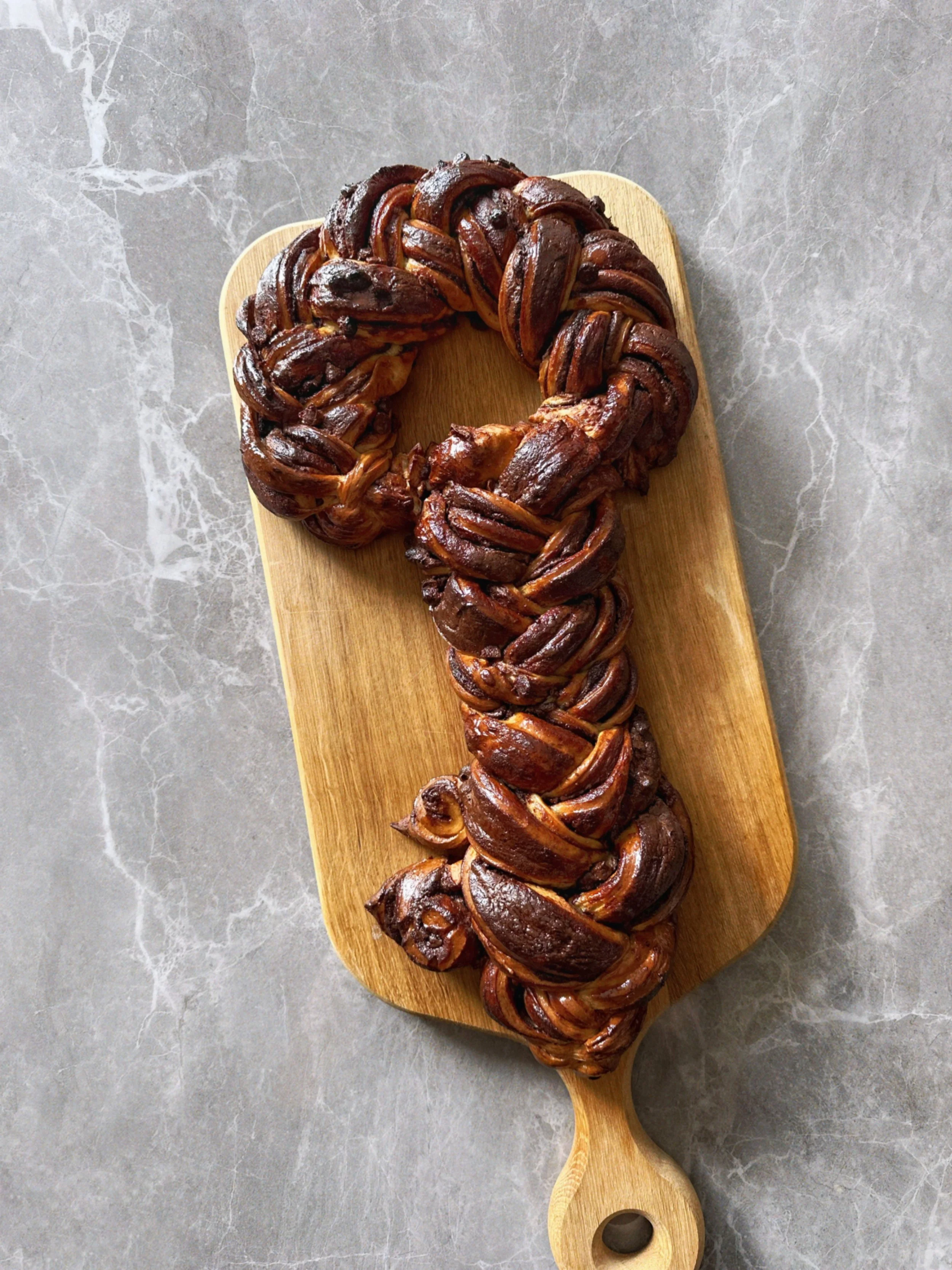Babka au chocolat en forme de couronne placé sur une planche en bois.