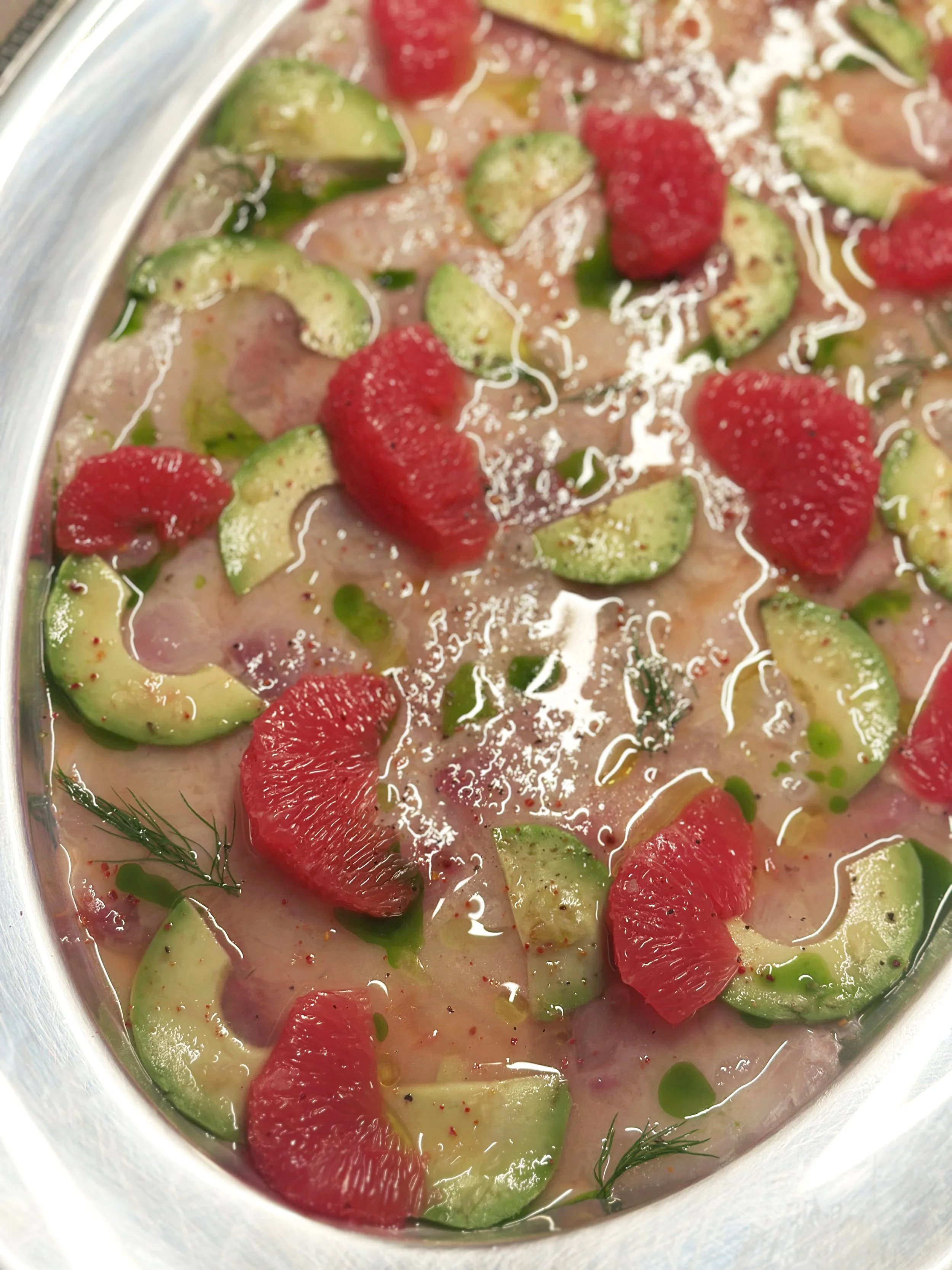 Tranches de concombre et de fraises dans un liquide, décorées de Fenouil et d'huile d olive.
