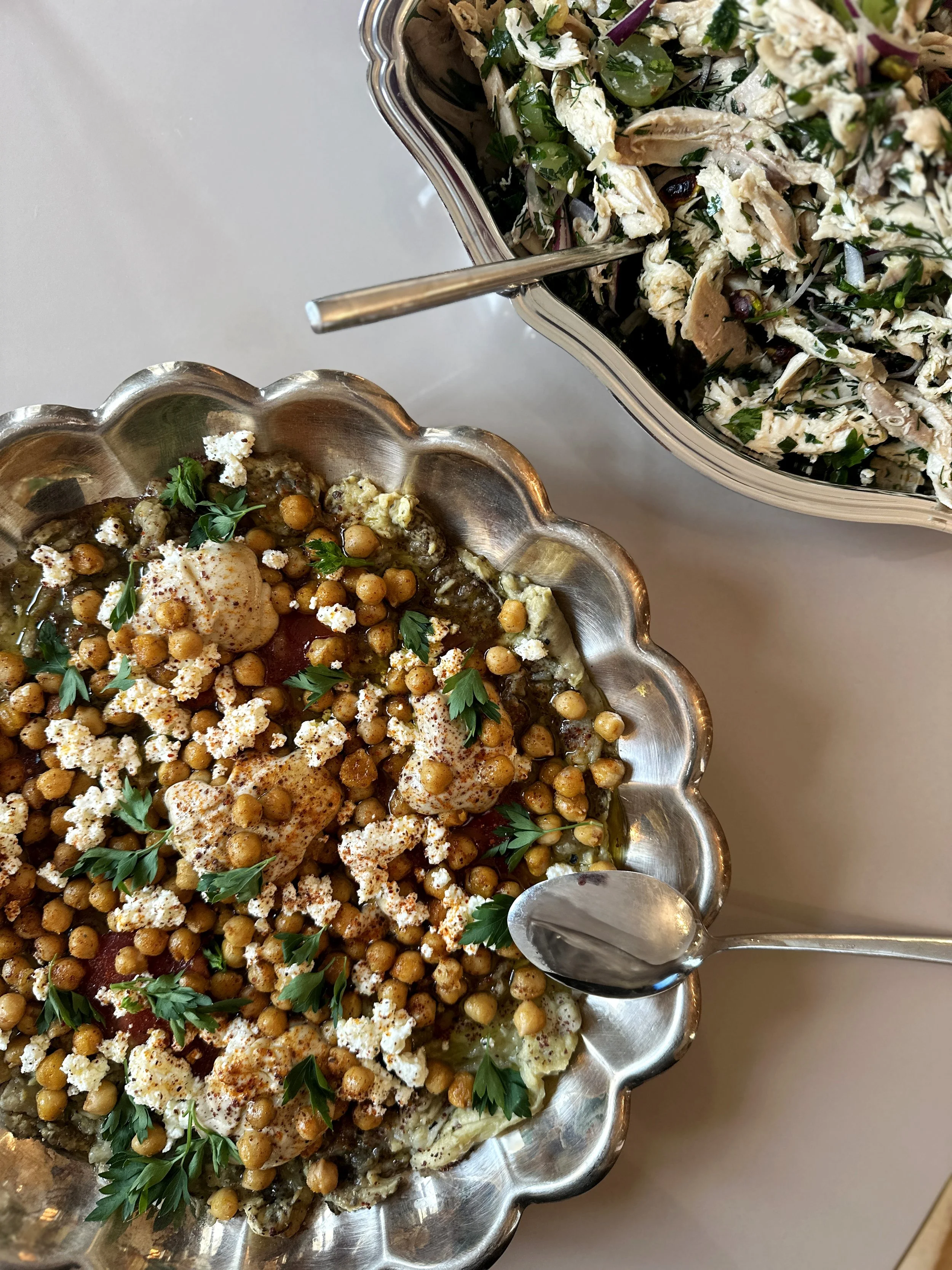 Deux plats de cuisine méditerranéenne, un plat de pois chiches, aubergine, tomates, feta, des herbes et du paprika , un salade avec poulet, olives, herbes et légumes.
