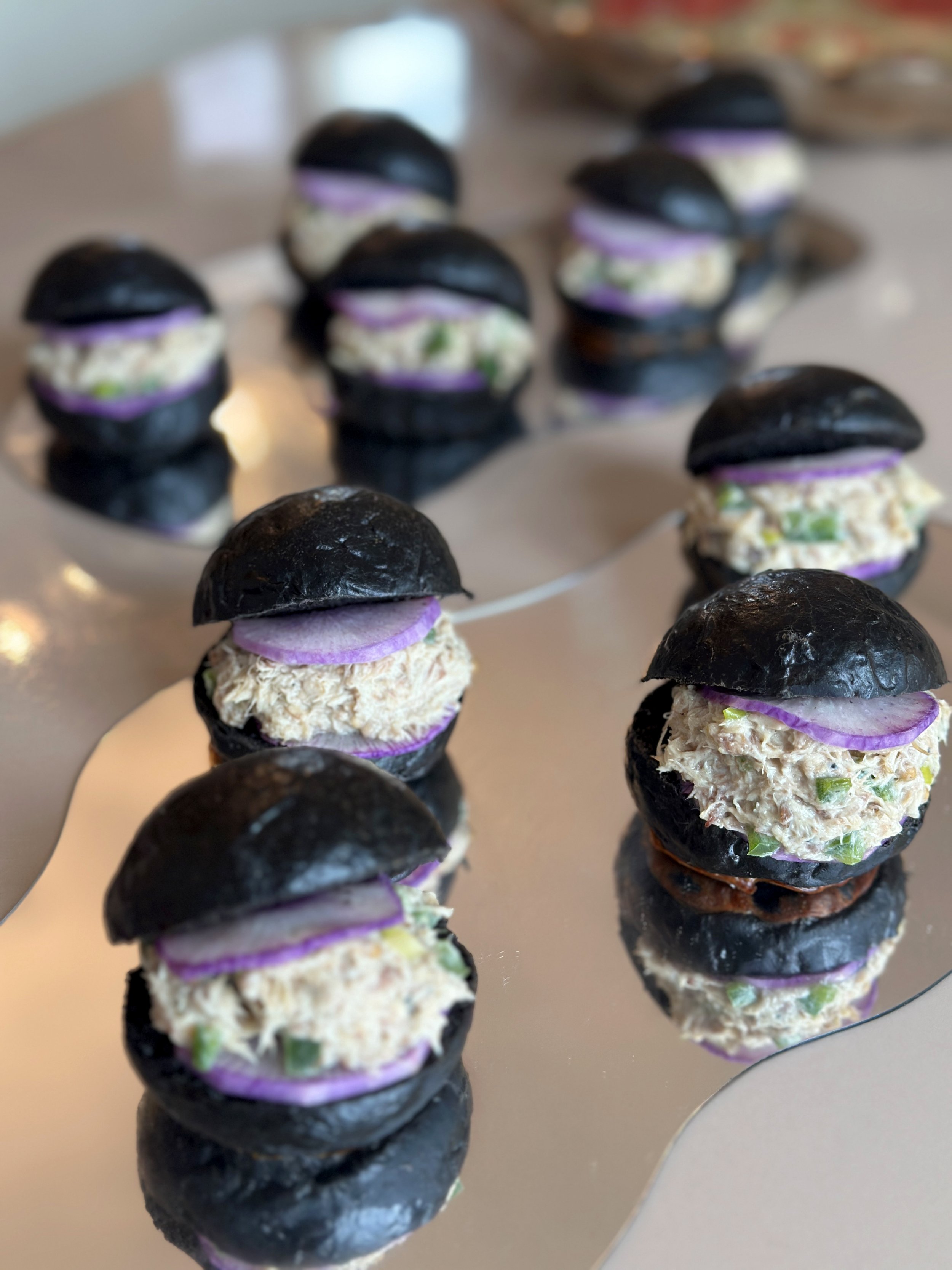Mini buns à l'encre de seiche, rillette de maquereau, des poivrons verts, citron confit, cébette, radis blue meat.