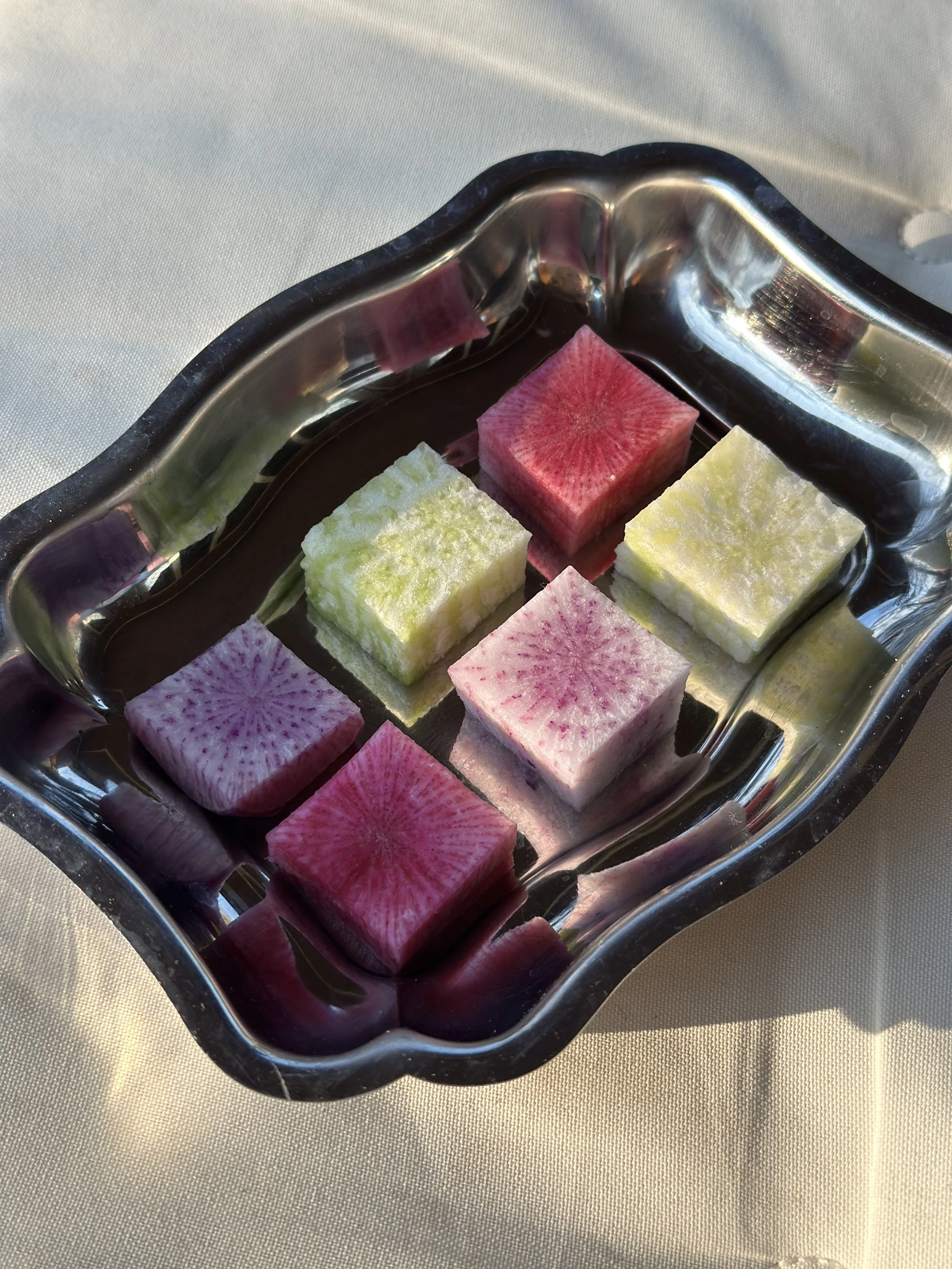 Des cubes de radis multicolores dans un plat en argent