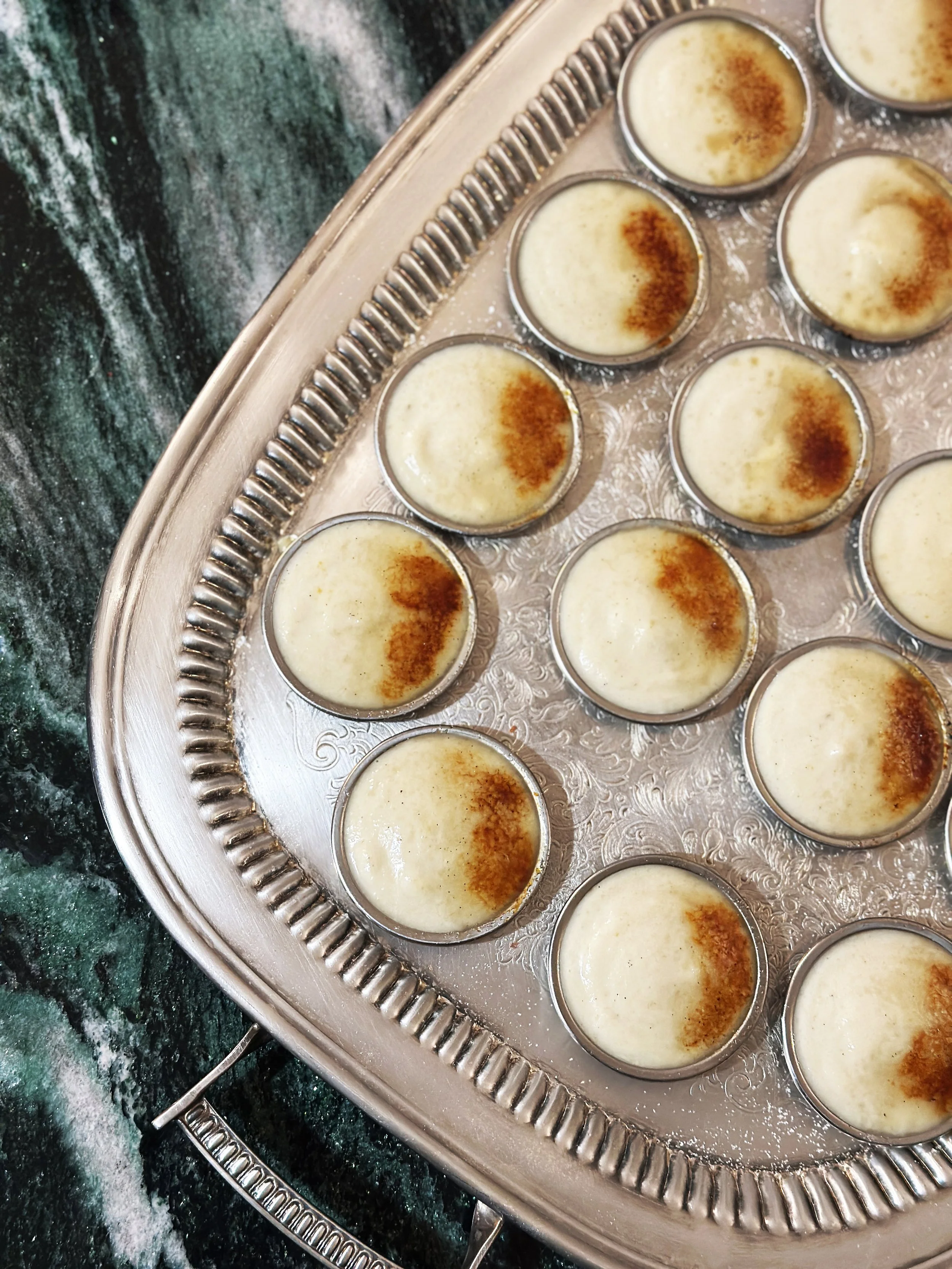 Crème brûlée dans des ramequins disposés sur un plateau en métal.
