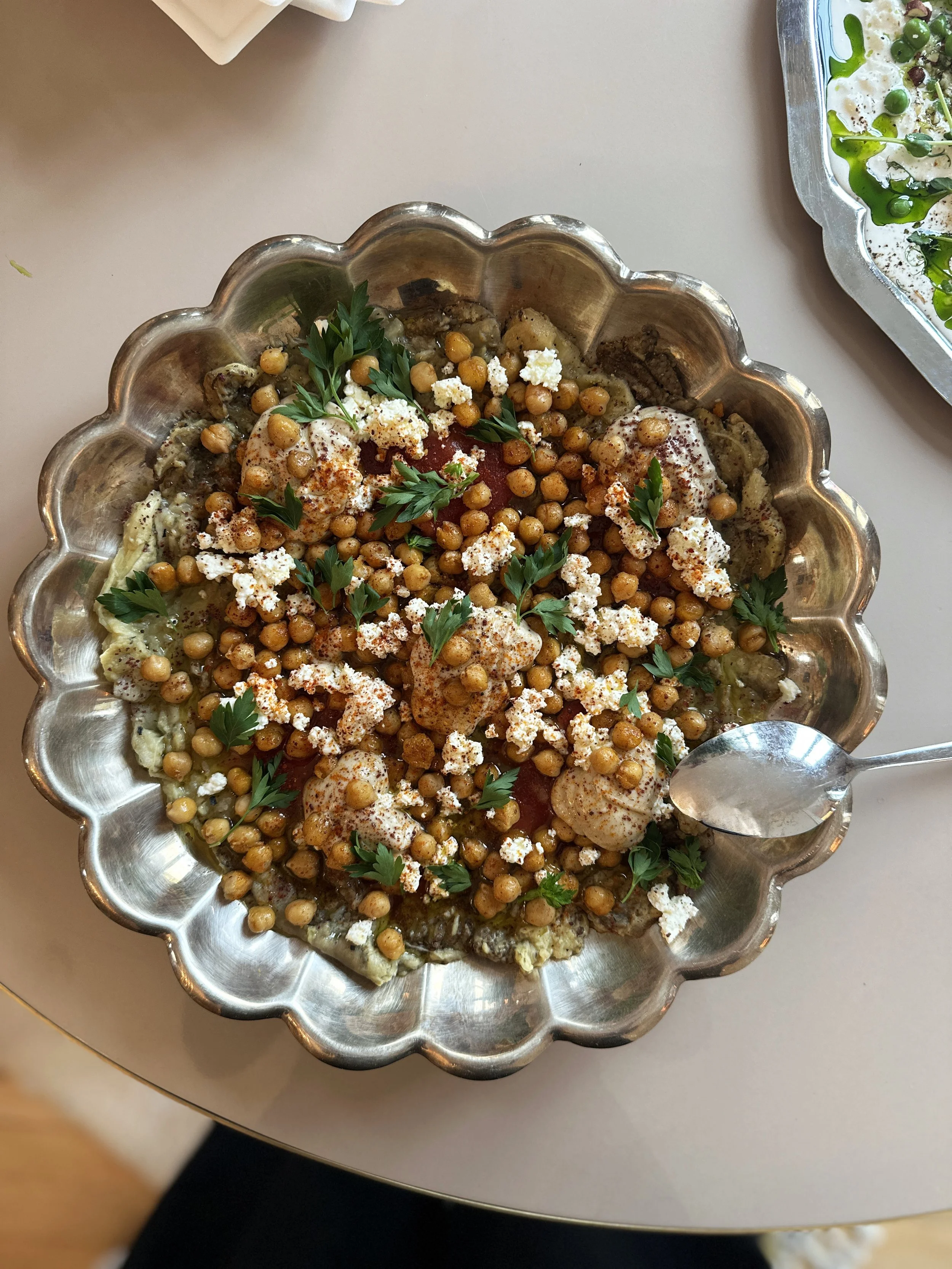 Plat de nourriture avec pois chiches, aubergine fumée, herbes fraîches, feta, et tahini