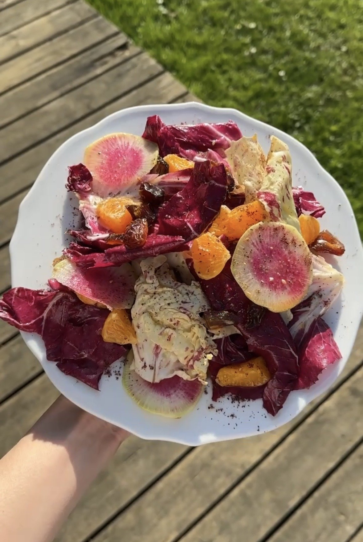 Salade colorée avec des tranches de radis, des morceaux de mandarine, des feuilles de salade radicchio et castelfranco