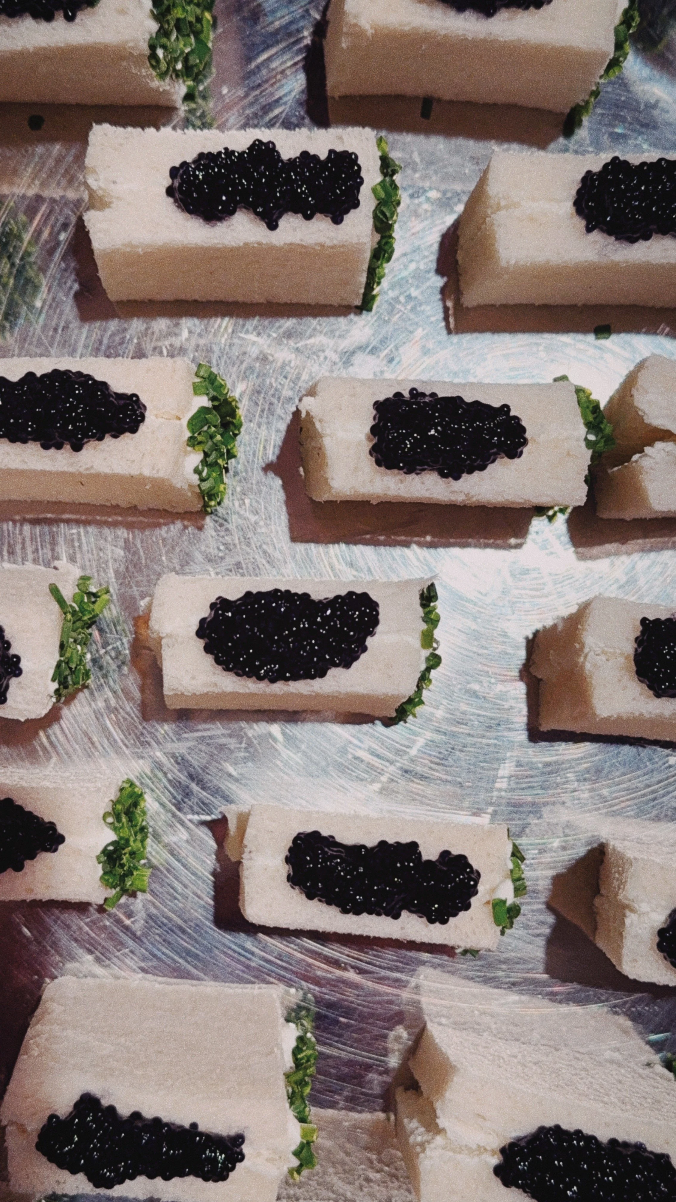 Des Barquettes de foie gras garnies de caviar et de verdure, disposées sur une surface métallique.