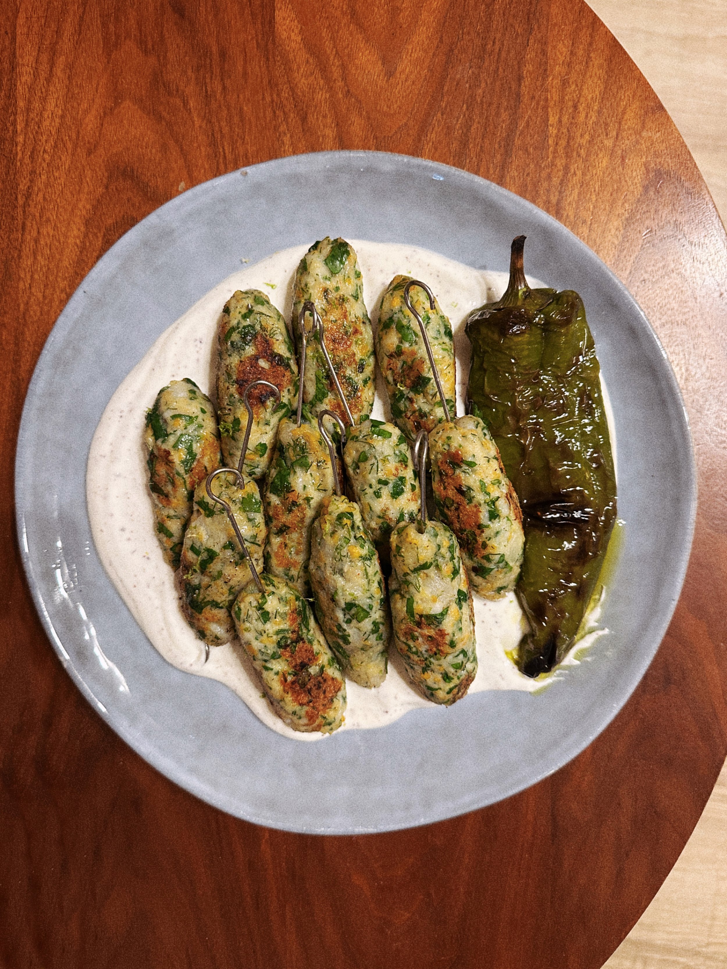 Assiette de kebab de poisson servie avec du yaourt et du poivron vert grillé