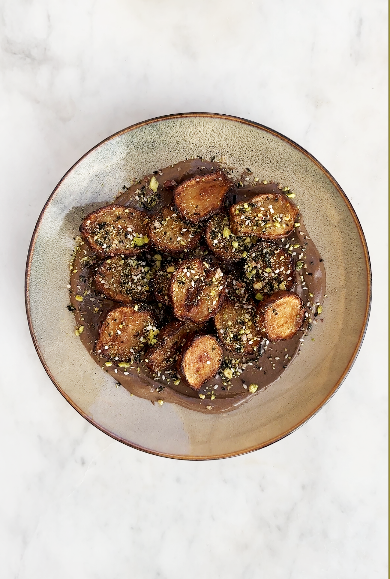 Les topinambours rotis et frits avec une sauce tahini à l'ail noir avec dukkah de pistache