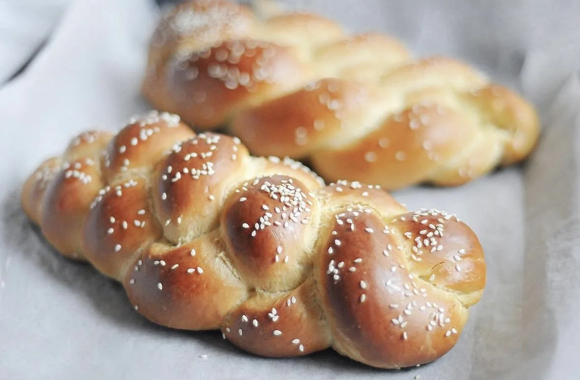 Deux hallot dorées avec des grains desésame dessus, posées sur du papier alimentaire.