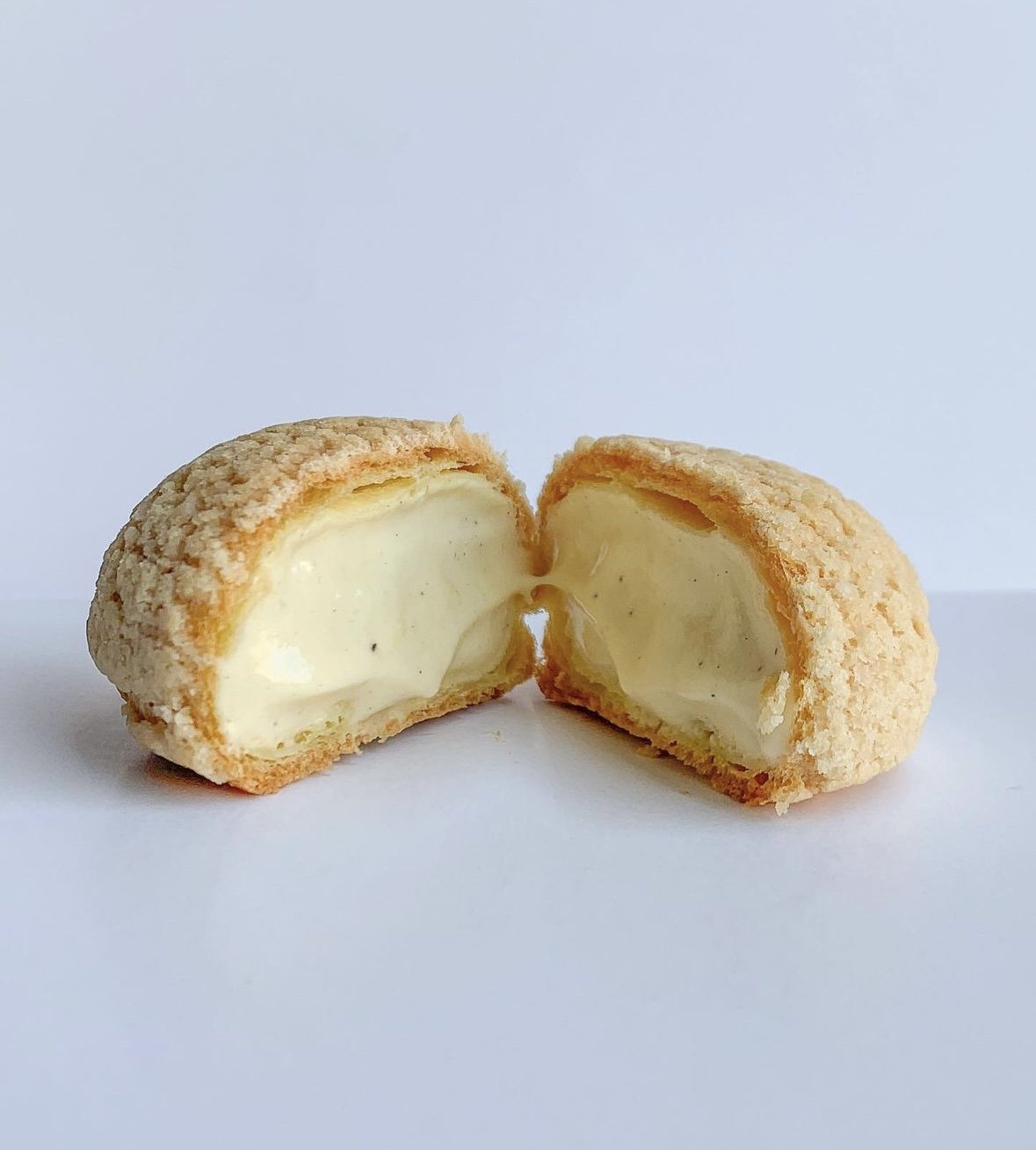Chou craquelin fourré à la crème, coupé en deux pour révéler la garniture crémeuse à l'intérieur.