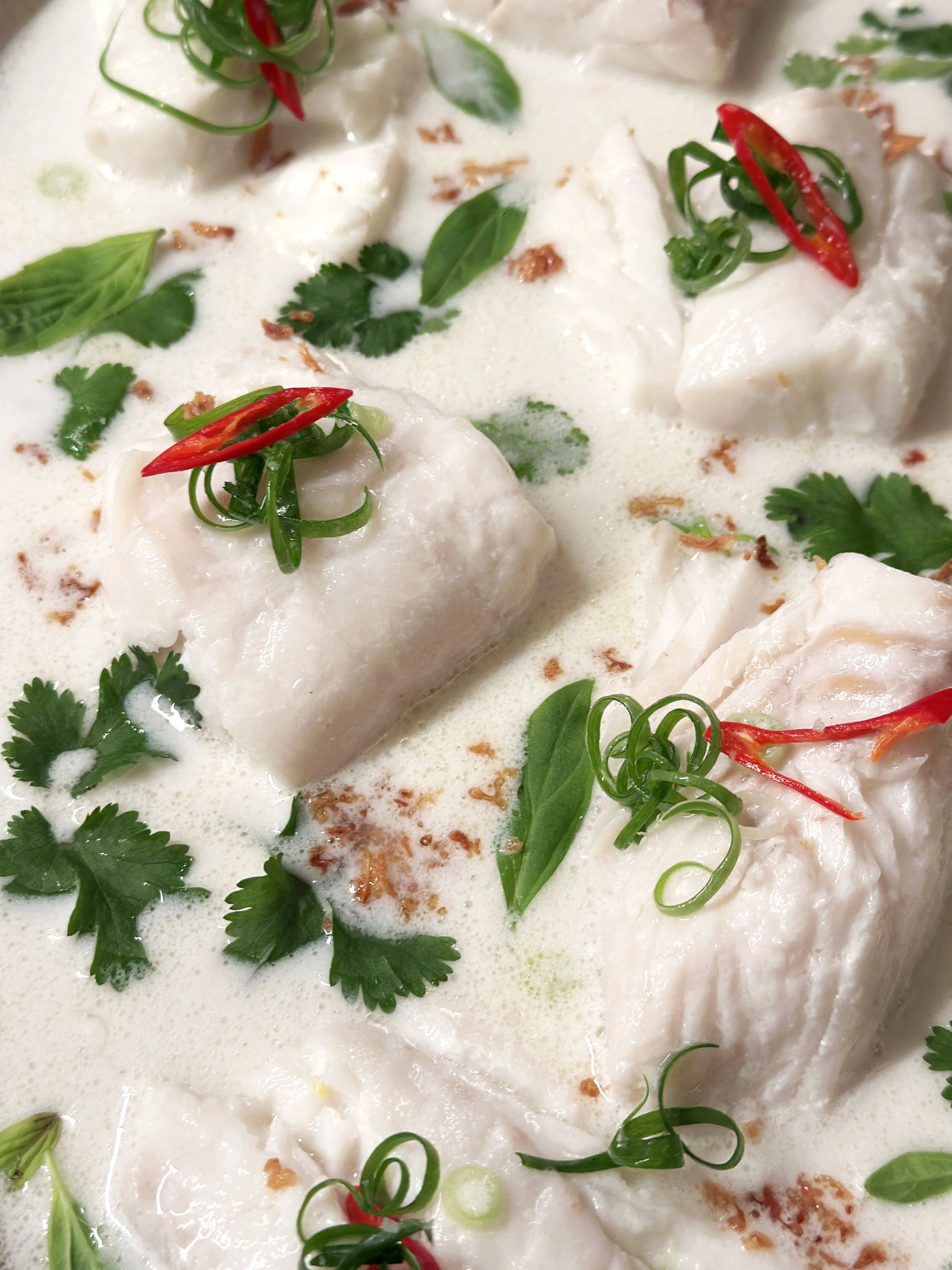 Plat de poisson en sauce à la crème avec herbes fraîches, piment rouge, coriandre, basilic et échalotes.