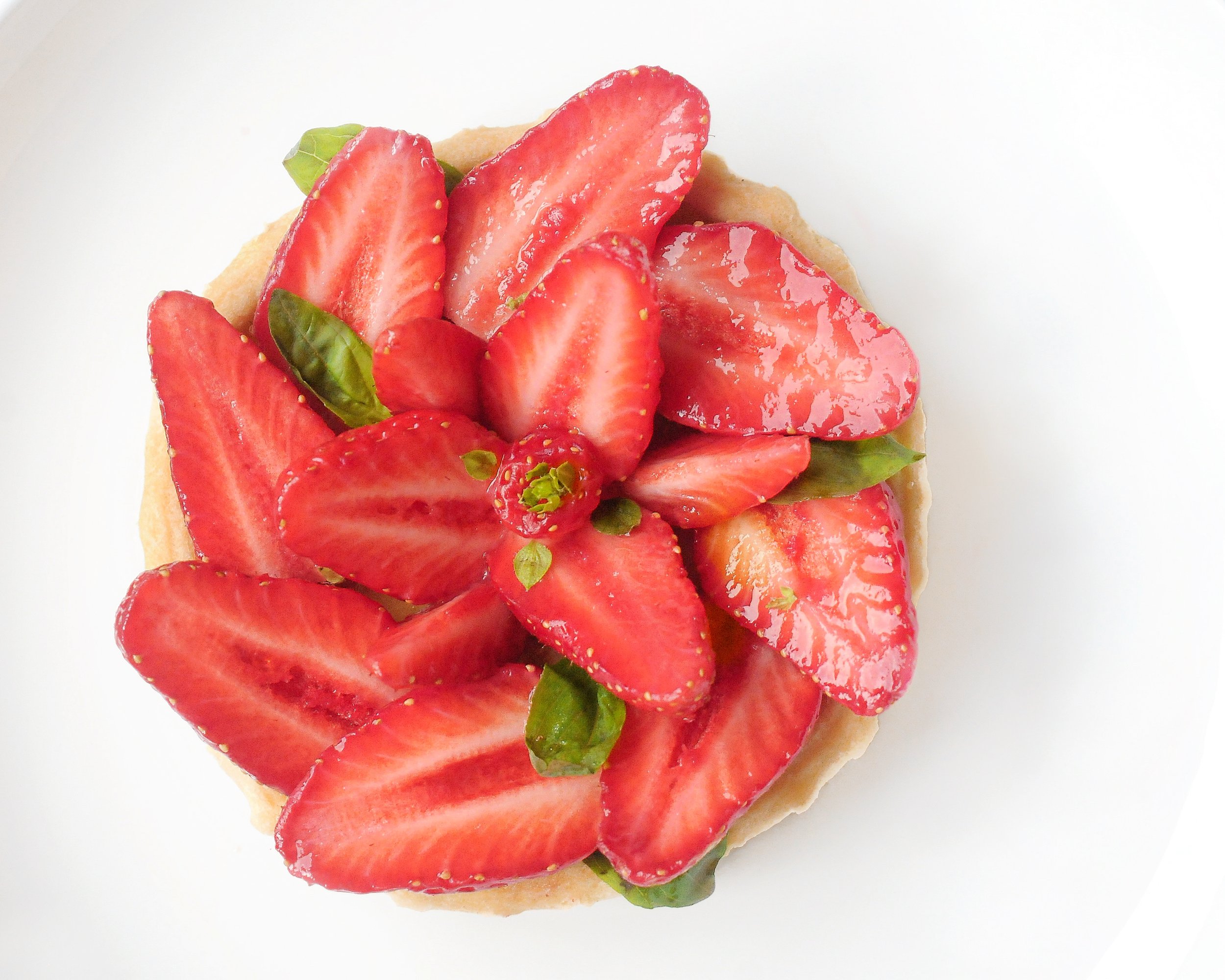 Tartelettes aux fraises garnies de fraises fraîches et de feuilles de basilic, vue du dessus.