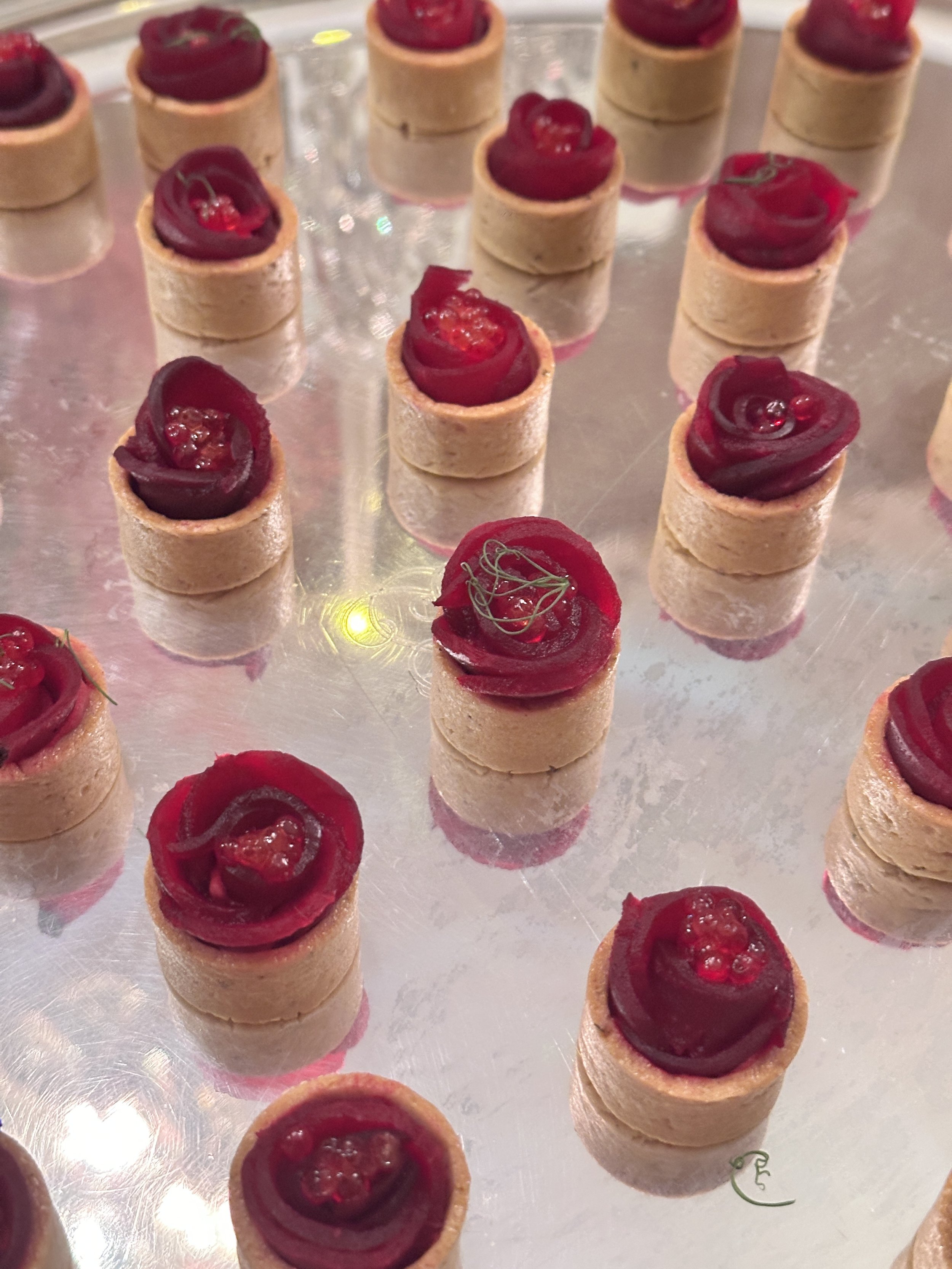 Mini tartelettes en rosace de betteraves, présentées sur une plaque en métal.