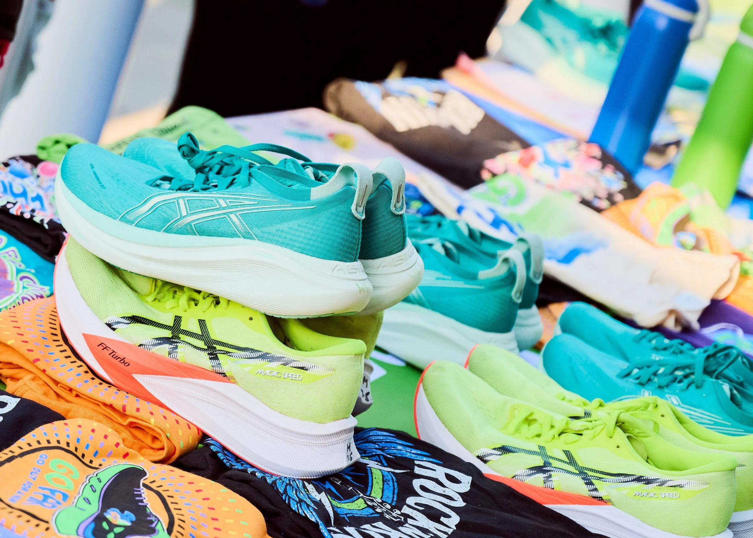 A row of colorful running shoes displayed on a table at a sporting event.