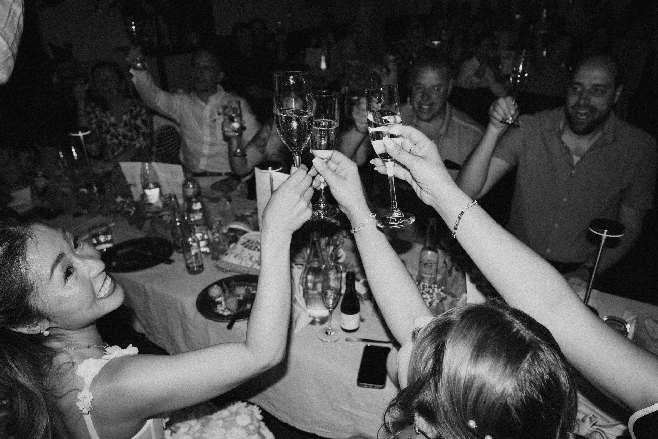 Guests raising champagne glasses in a toast at a wedding celebration, representing joy, commitment, and a successful long-term relationship.