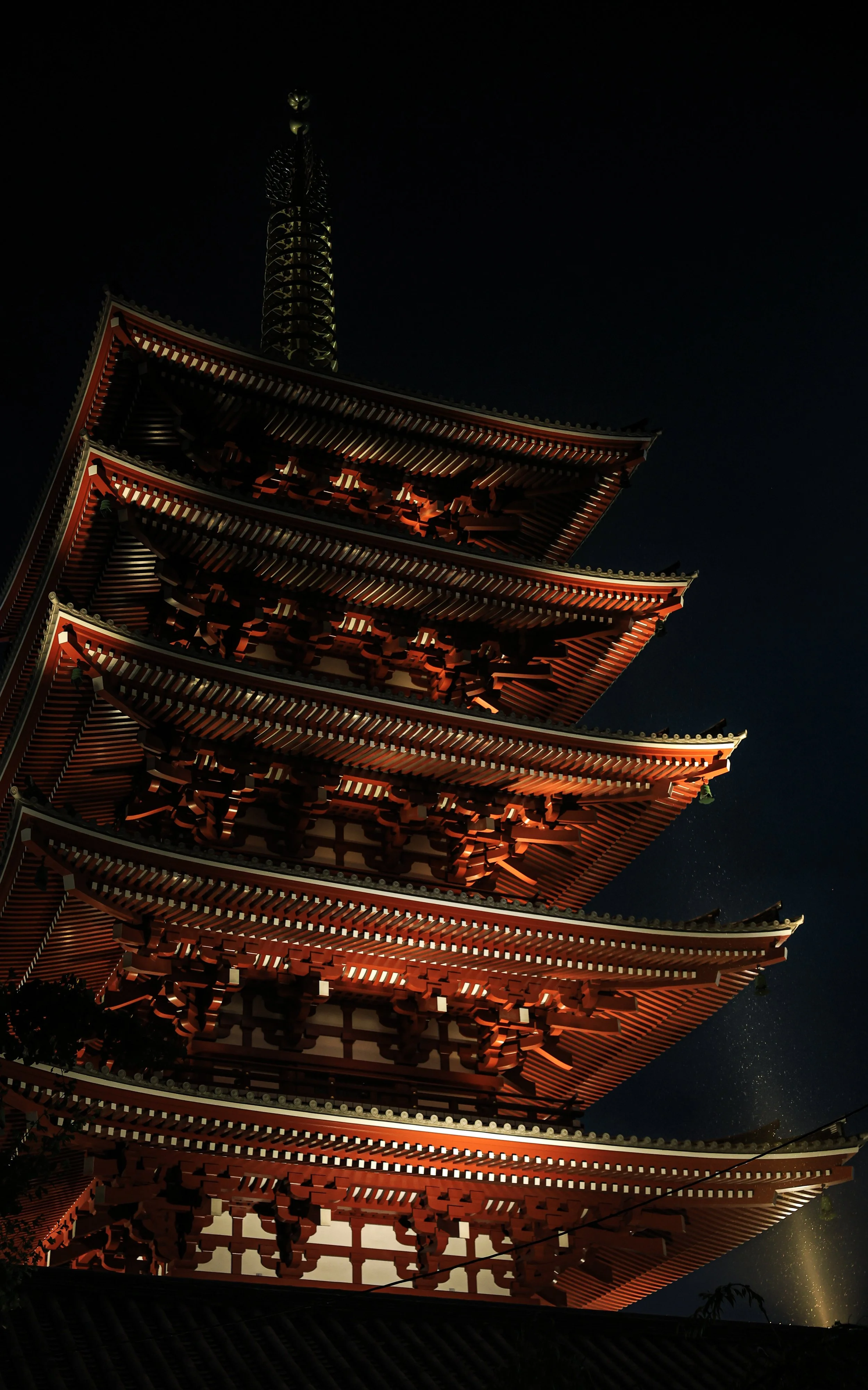 Night view of Sensoji Temple illuminated from below, with a dark night sky in the background.