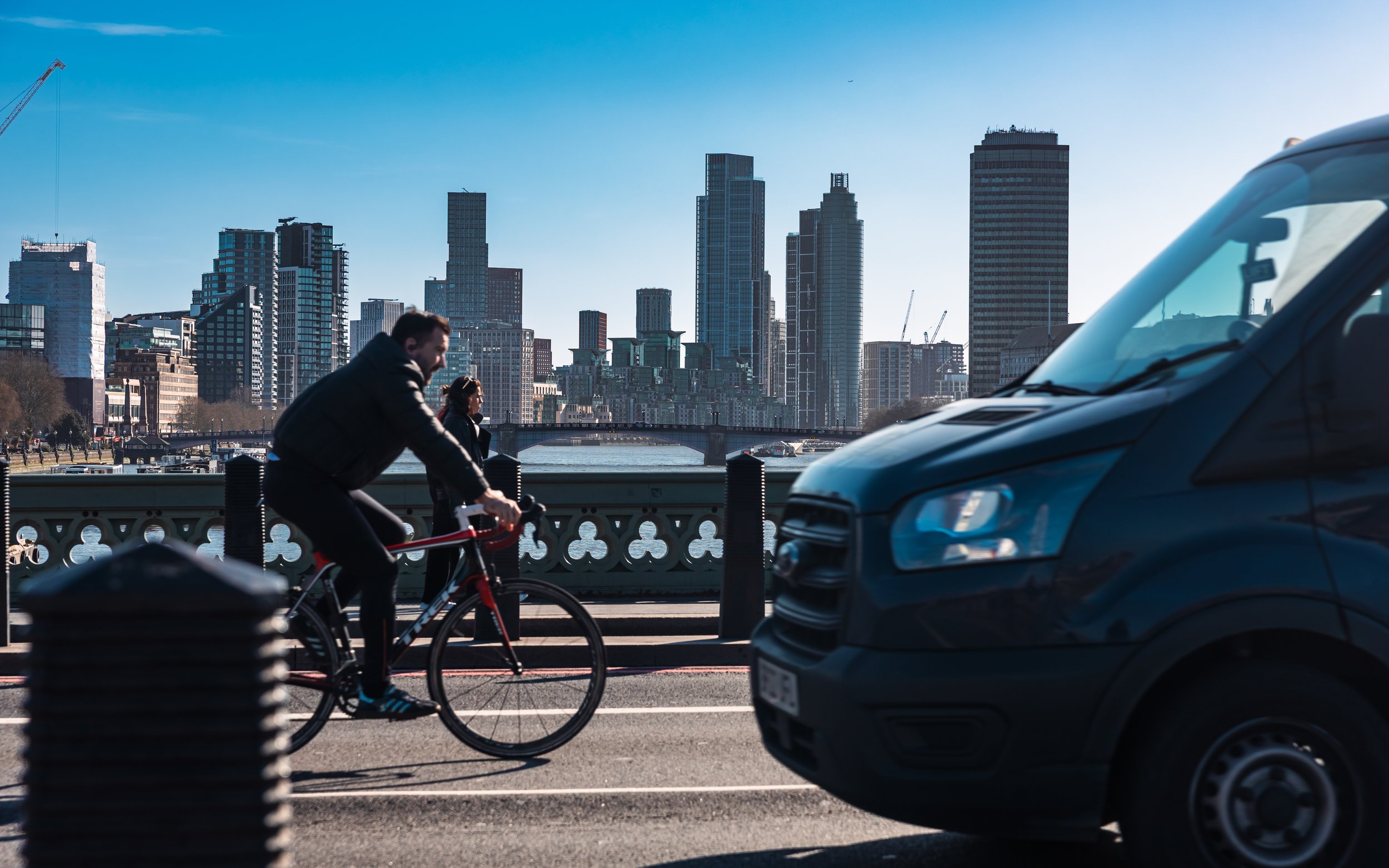 A record of a bustling bridge in London, with the city skyline in the background and a dark van partially visible in the foreground.
Taken in London