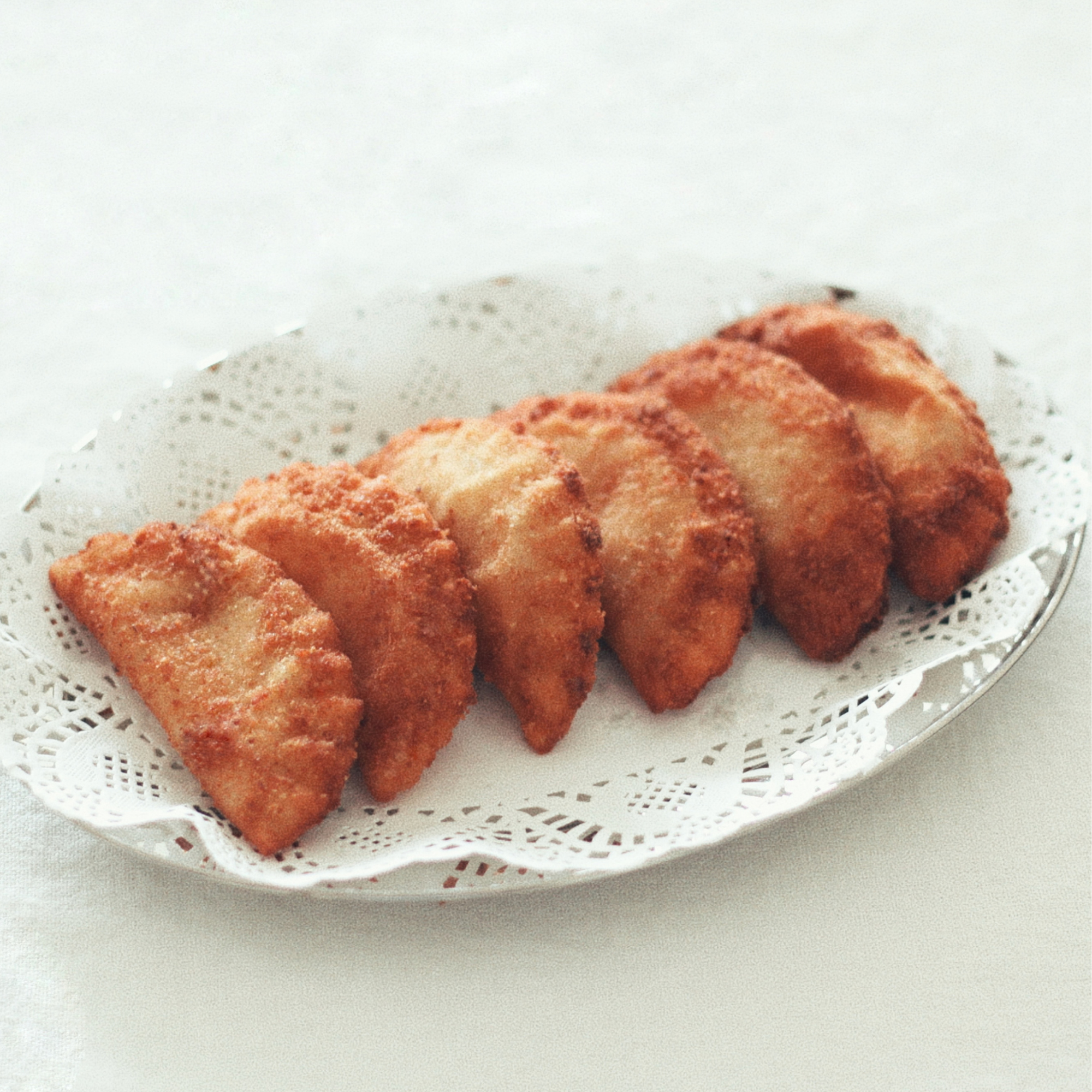 Assorted handmade Portuguese rissois with shrimp and chouriço fillings, arranged on a white serving platter.