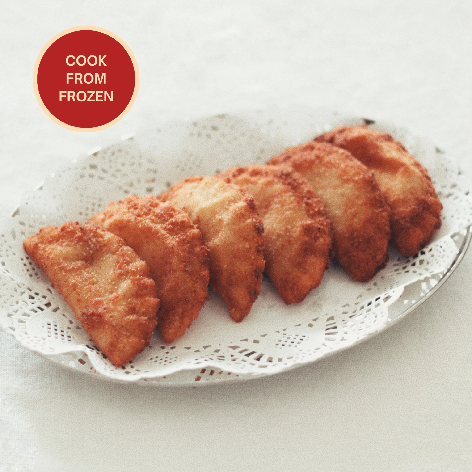 Golden Portuguese rissois served on a white platter, available frozen from Rissolá to fry fresh at home.