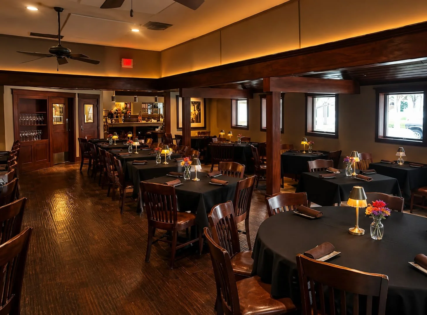 Elegant dining room with tables set for dinner, full bar with wine selection, and warm amber lighting at Leelanau Steakhouse Seafood & Pasta
