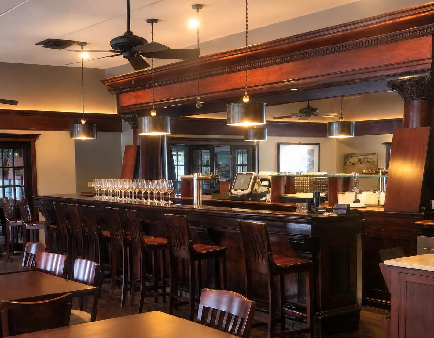 Full bar with wine glasses and selection, modern pendant lighting, and elegant wood accents at Leelanau Steakhouse Seafood & Pasta