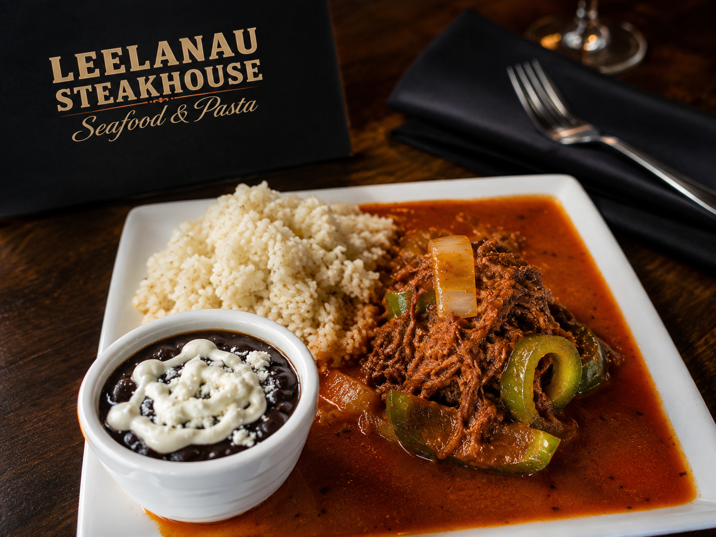 Plate of beef stew with rice, black beans with cheese, and a side of couscous at Leelanau Steakhouse.