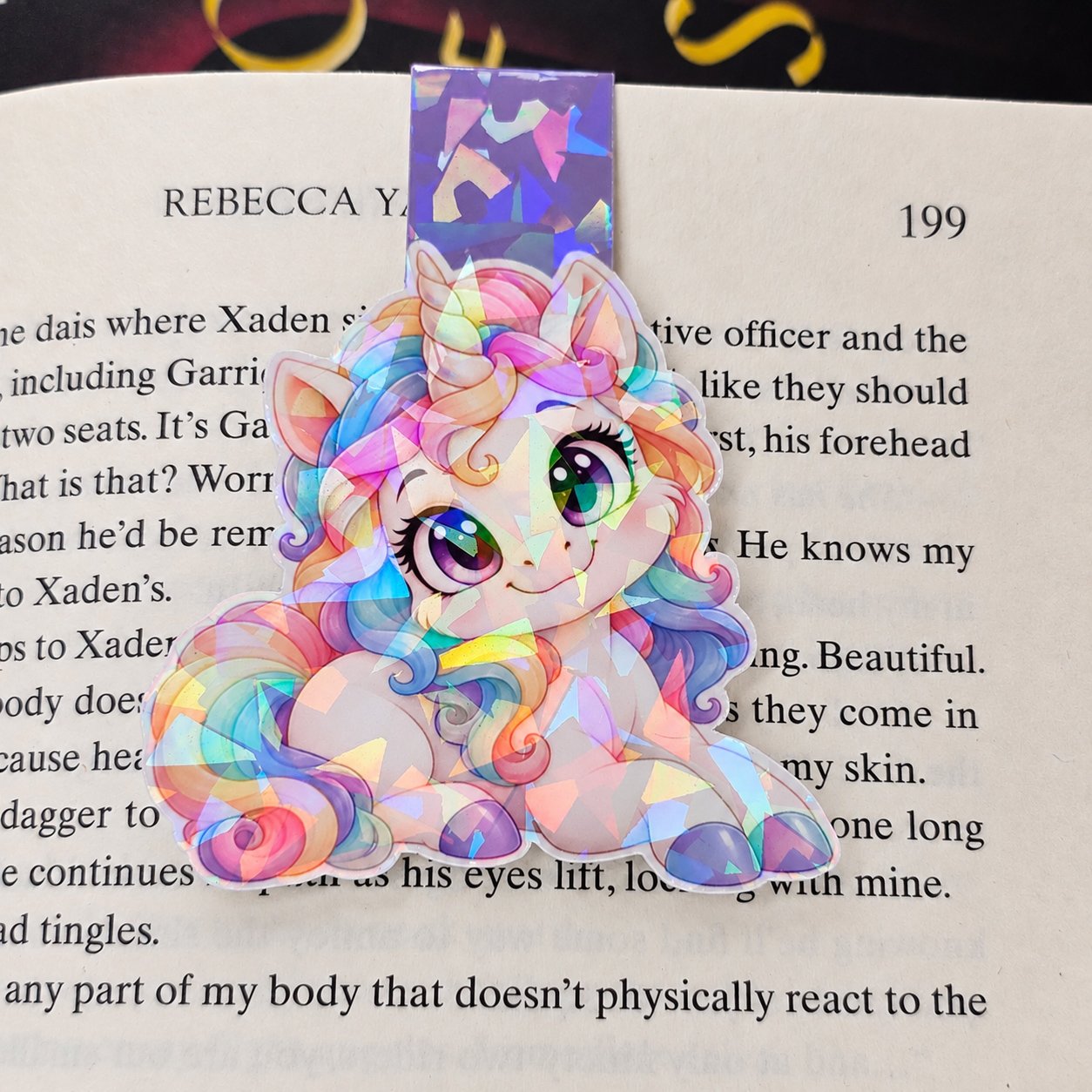 Holographic double-sided magnetic bookmark featuring a white unicorn with a flowing pastel rainbow mane and a purple tab.