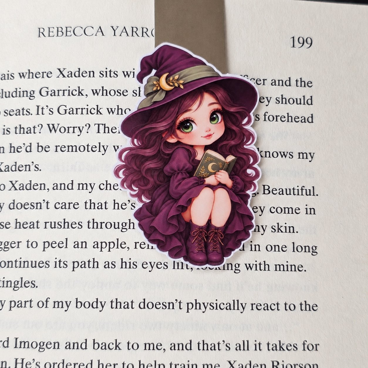 Double-sided magnetic bookmark featuring a purple-haired witch holding a book, wearing a plum dress and crescent moon hat.