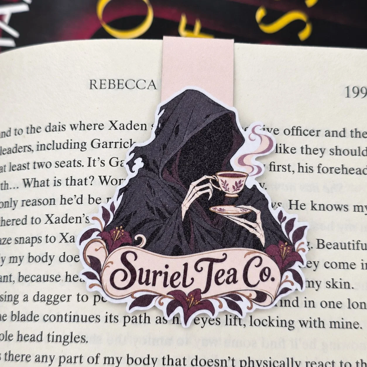 Double-sided magnetic bookmark featuring a faceless hooded figure holding a teacup above a floral “Suriel Tea Co.” banner.