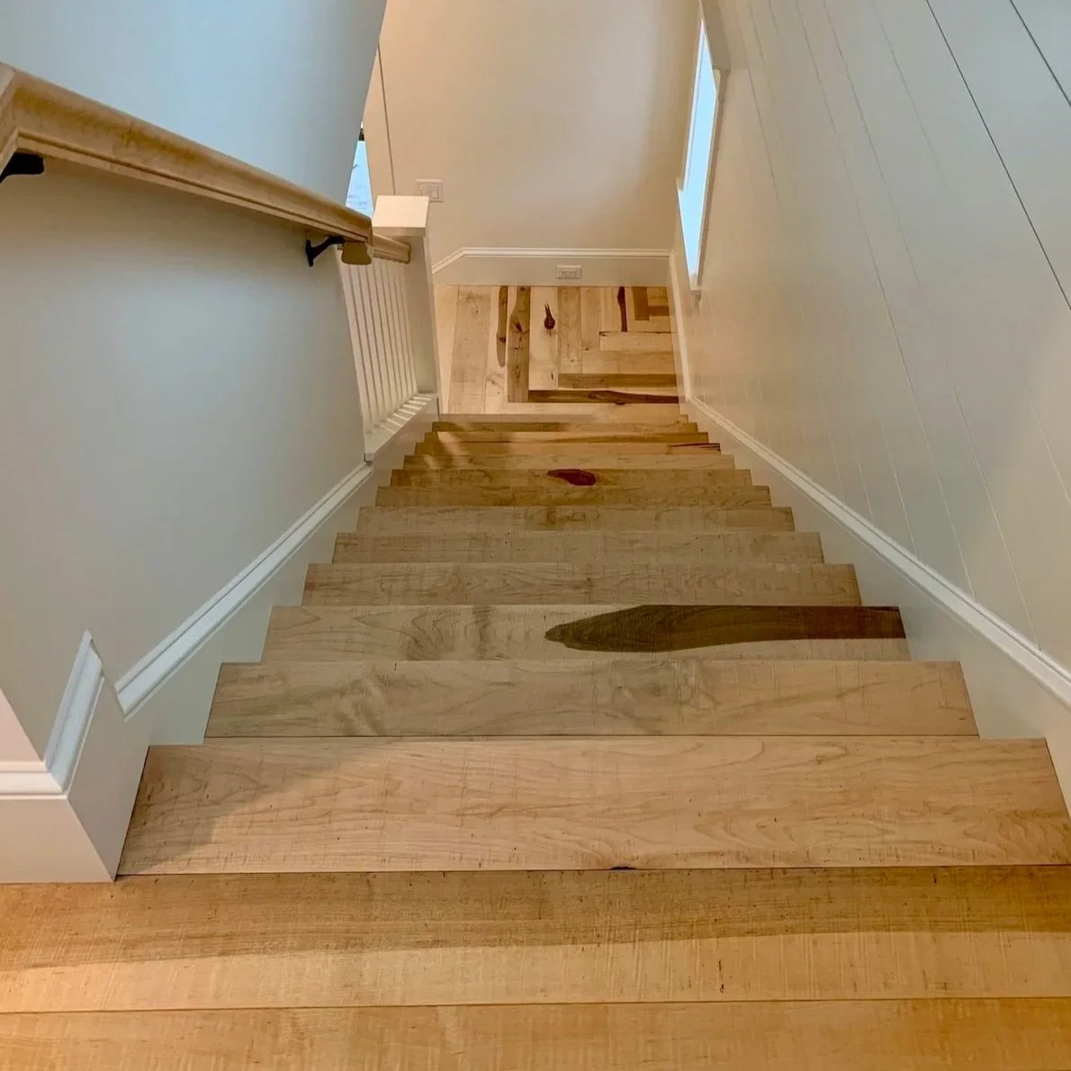 Custom wide plank staircase with wood treads and black metal balusters by Red Mountain Construction in Arlington, Vermon