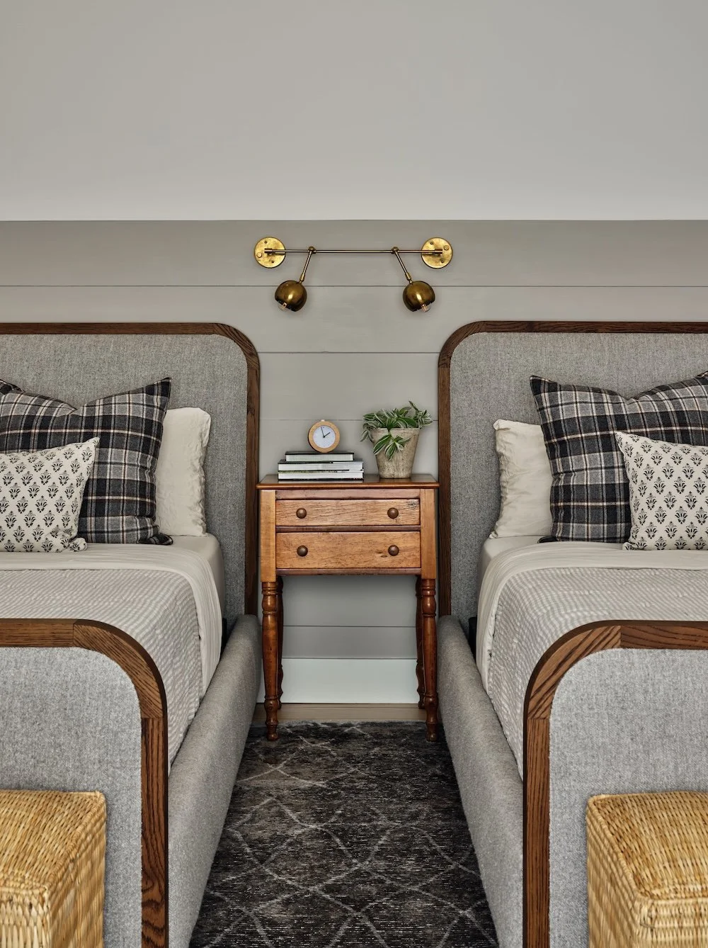 Bedroom in a renovated home in Dorset, Vermont, with two twin beds, upholstered headboards, and a shared nightstand with brass wall sconces above.