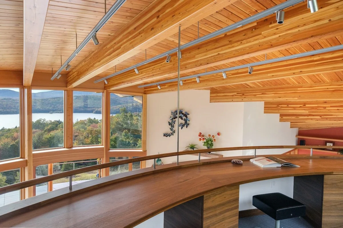 Upper-level interior of a custom home in Wilmington, Vermont, with exposed wood structure, a curved railing, and elevated views across the landscape.