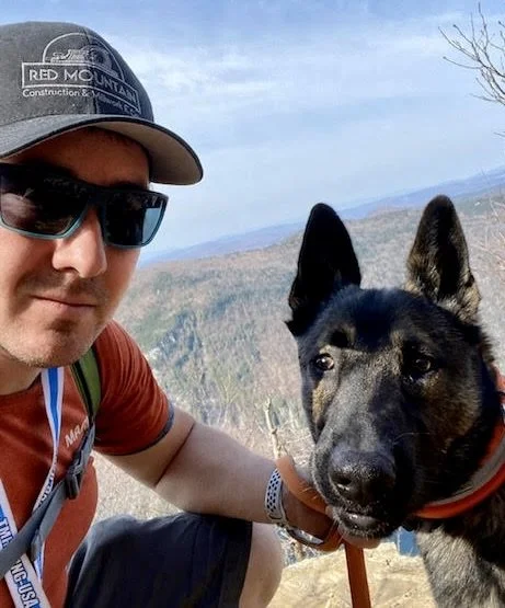 Portrait of Justin Albin, Vice President of Red Mountain Construction. Arlington, VT, hiking with his dog