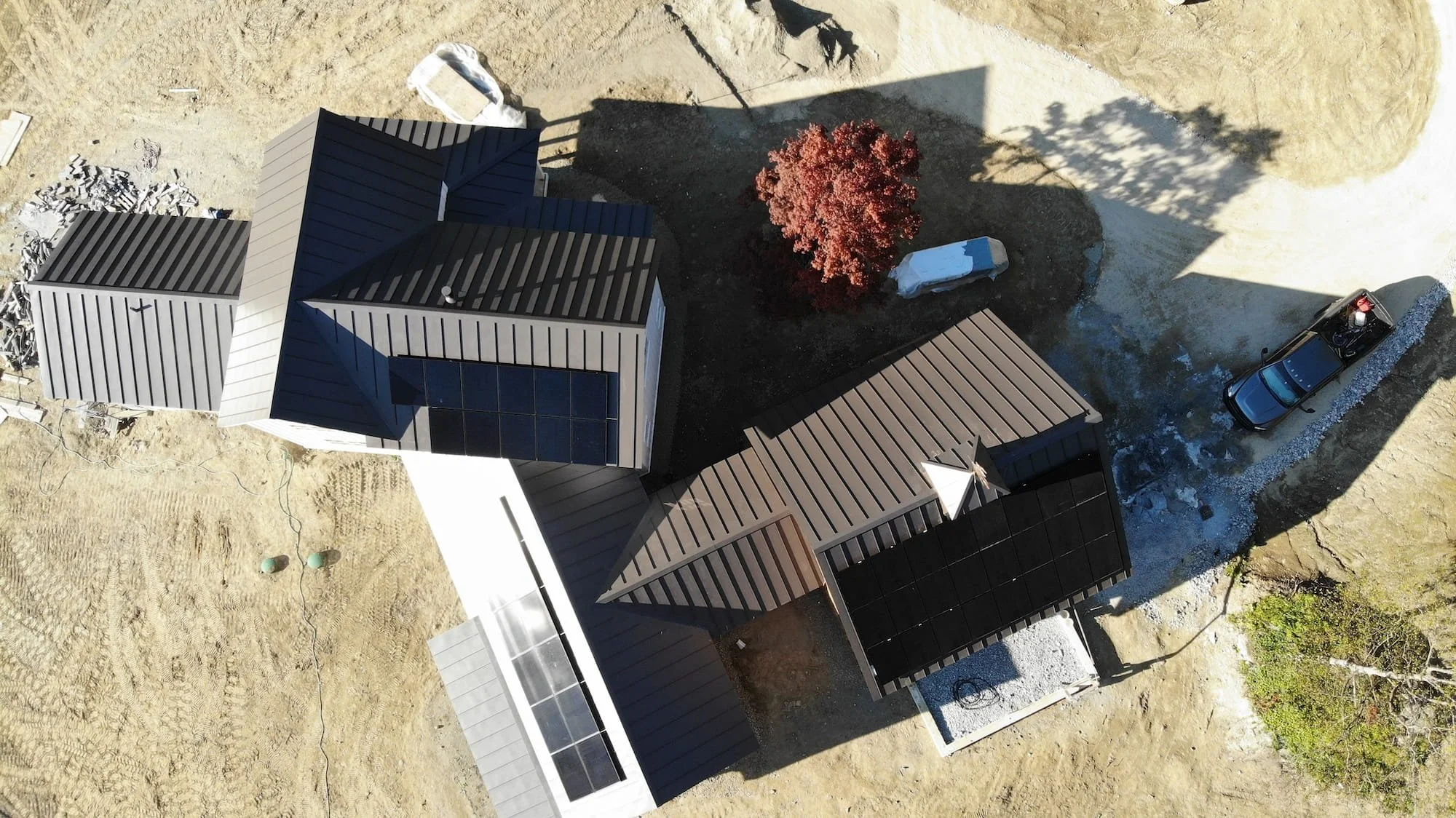 Aerial view of a custom home in Dorset, Vermont with a standing seam metal roof and solar panels, set within a spacious rural landscape.