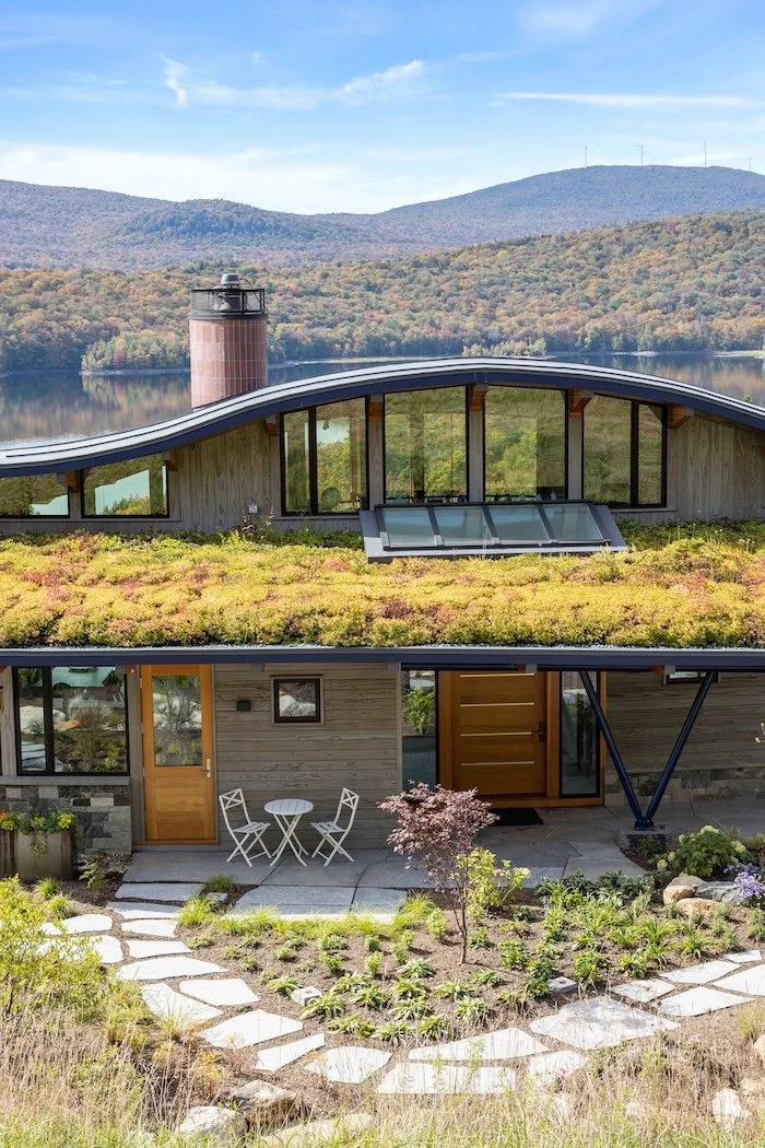 Front exterior of a custom home in Wilmington, Vermont, with a planted roof, curved forms, and a curving stone walkway leading to the entry.