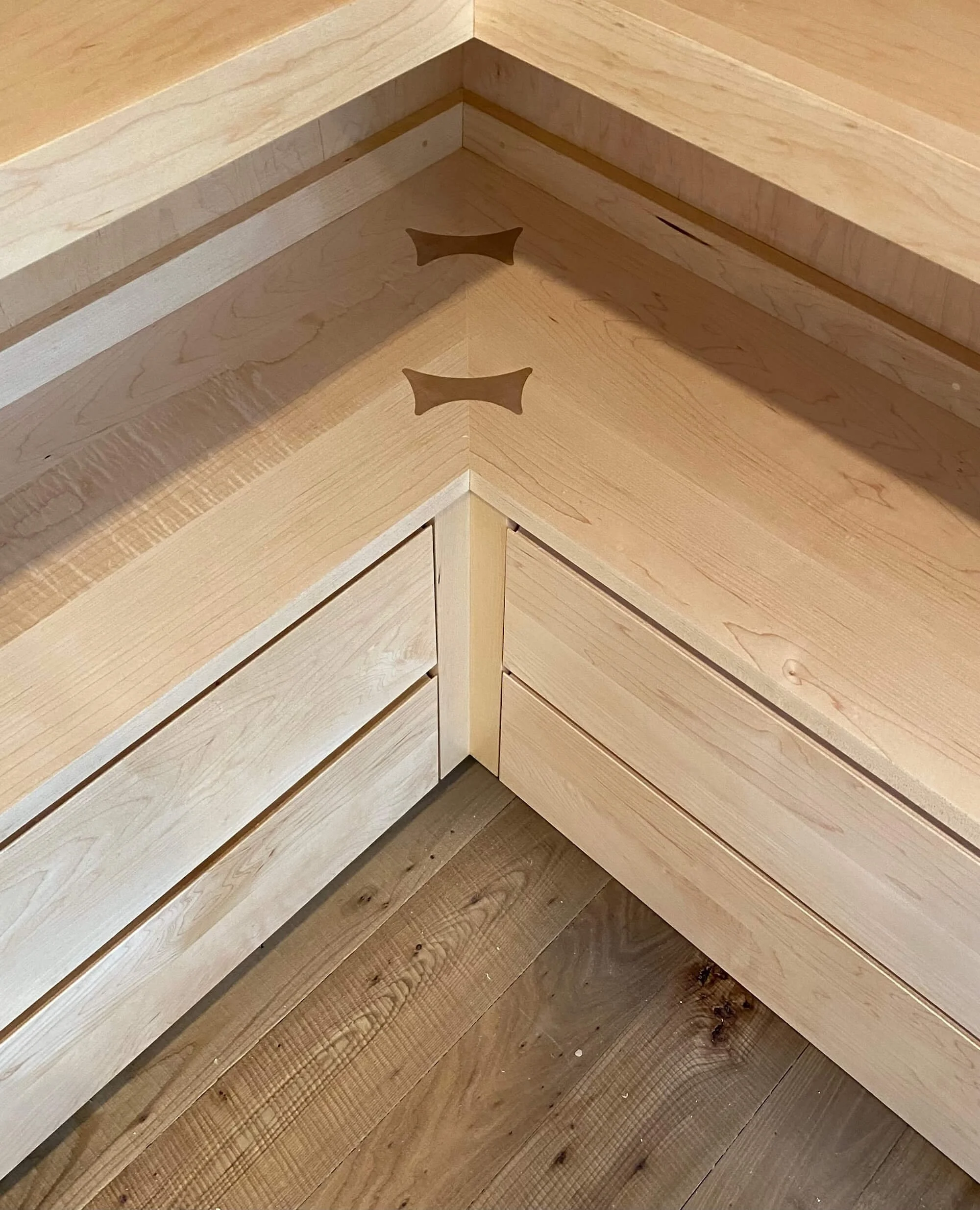 Corner millwork detail in a custom home in West Arlington, Vermont, with layered light wood joinery and a geometric inlay.