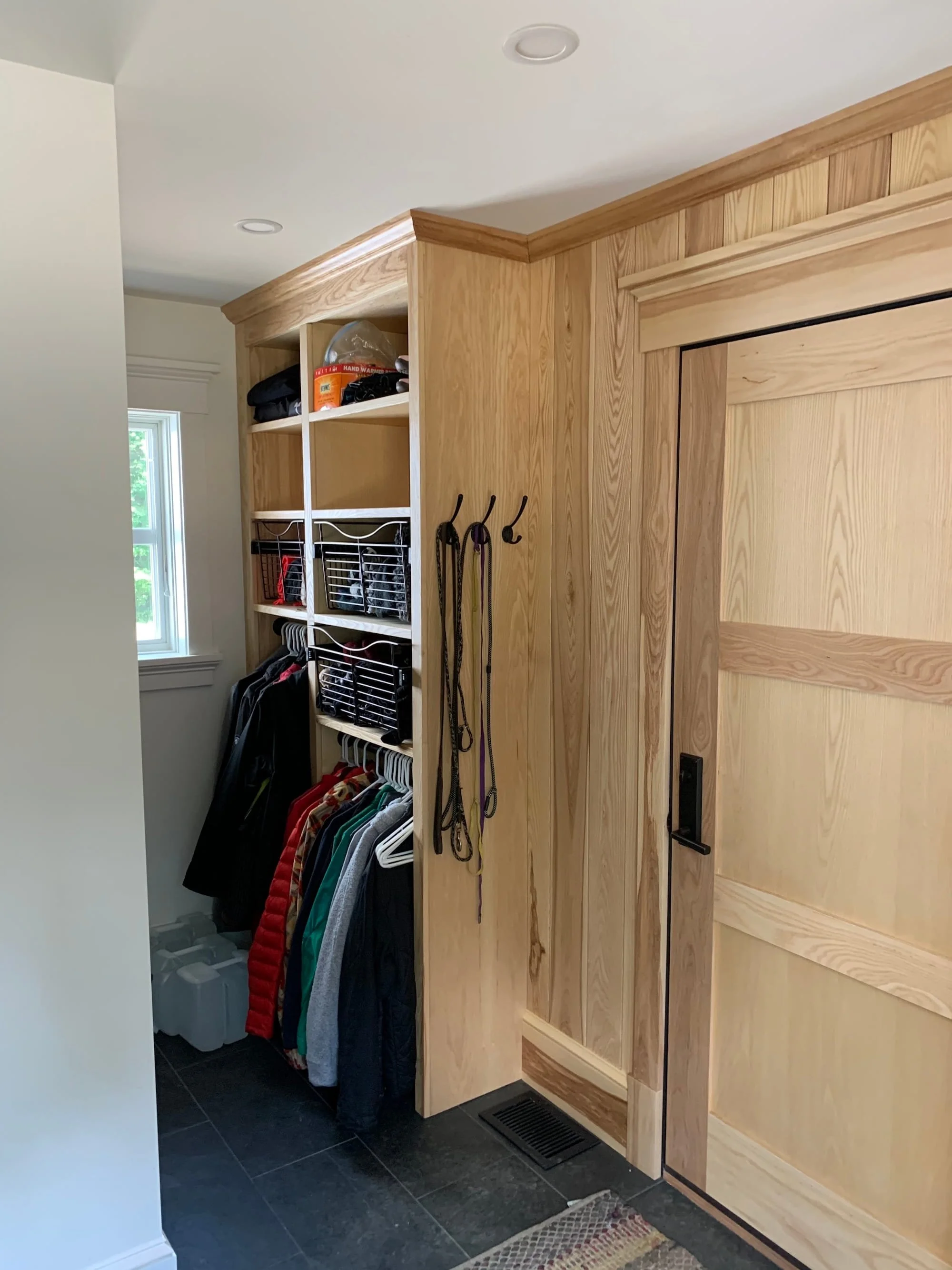 Mudroom in a custom home in Dorset, Vermont, with built-in wood cabinetry slate tile flooring.