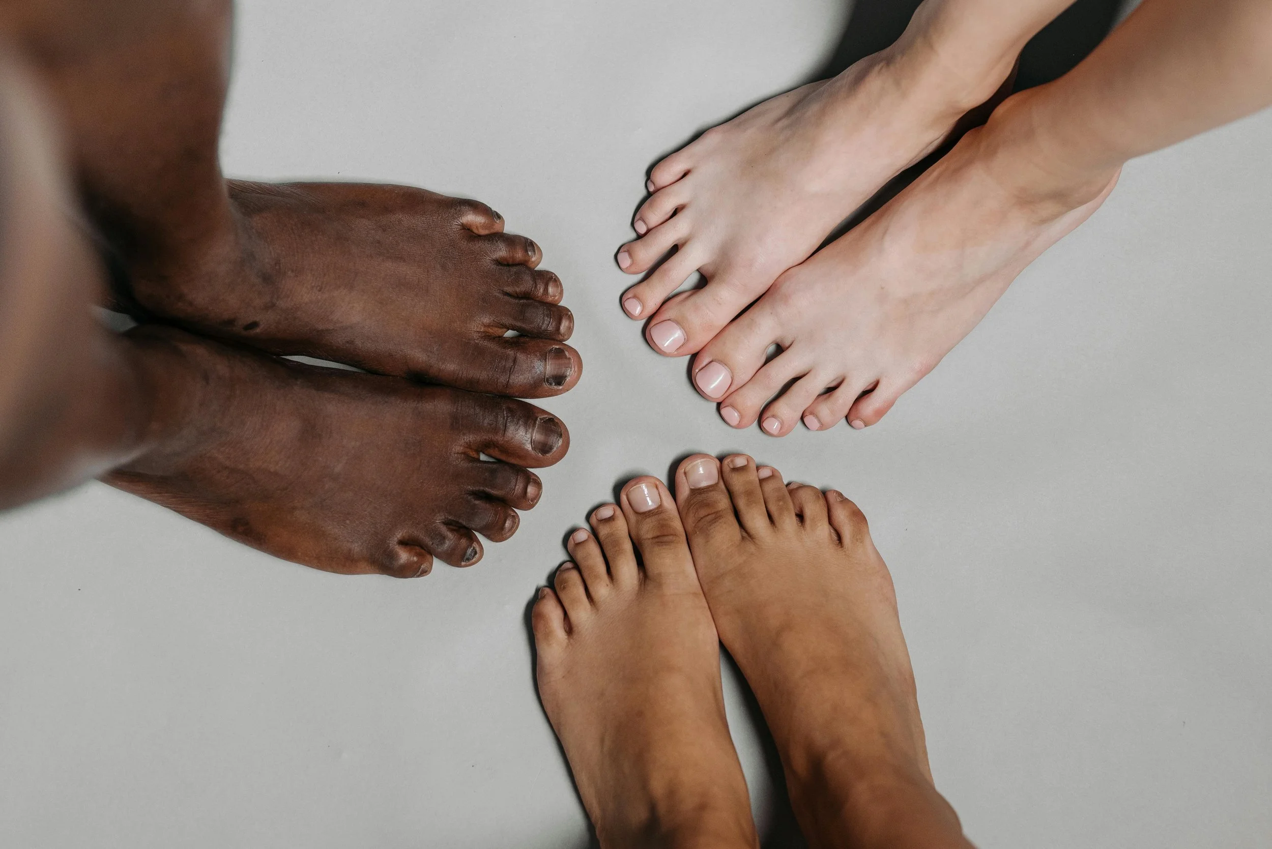 Multiple hands and feet of different skin tones arranged on a flat surface.