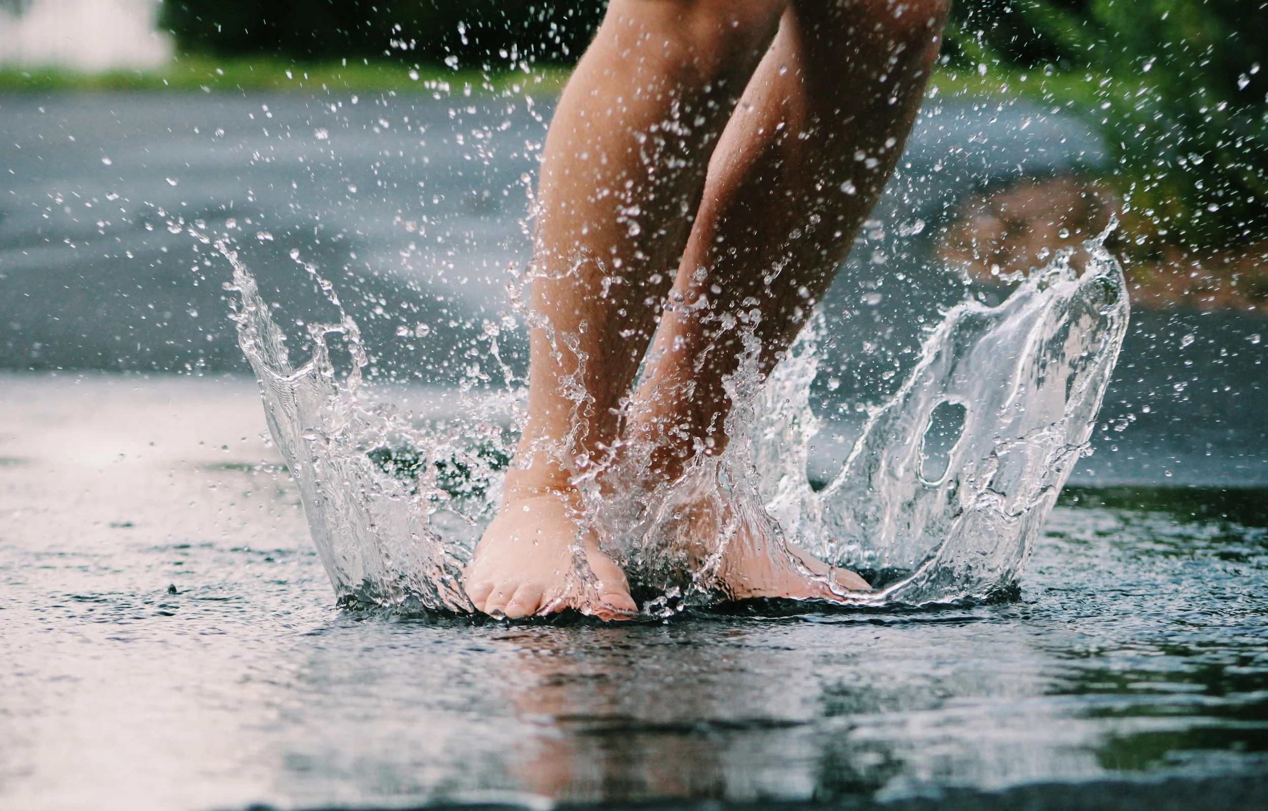 Close-up of a person's legs and feet splashing in shallow water during daytime
