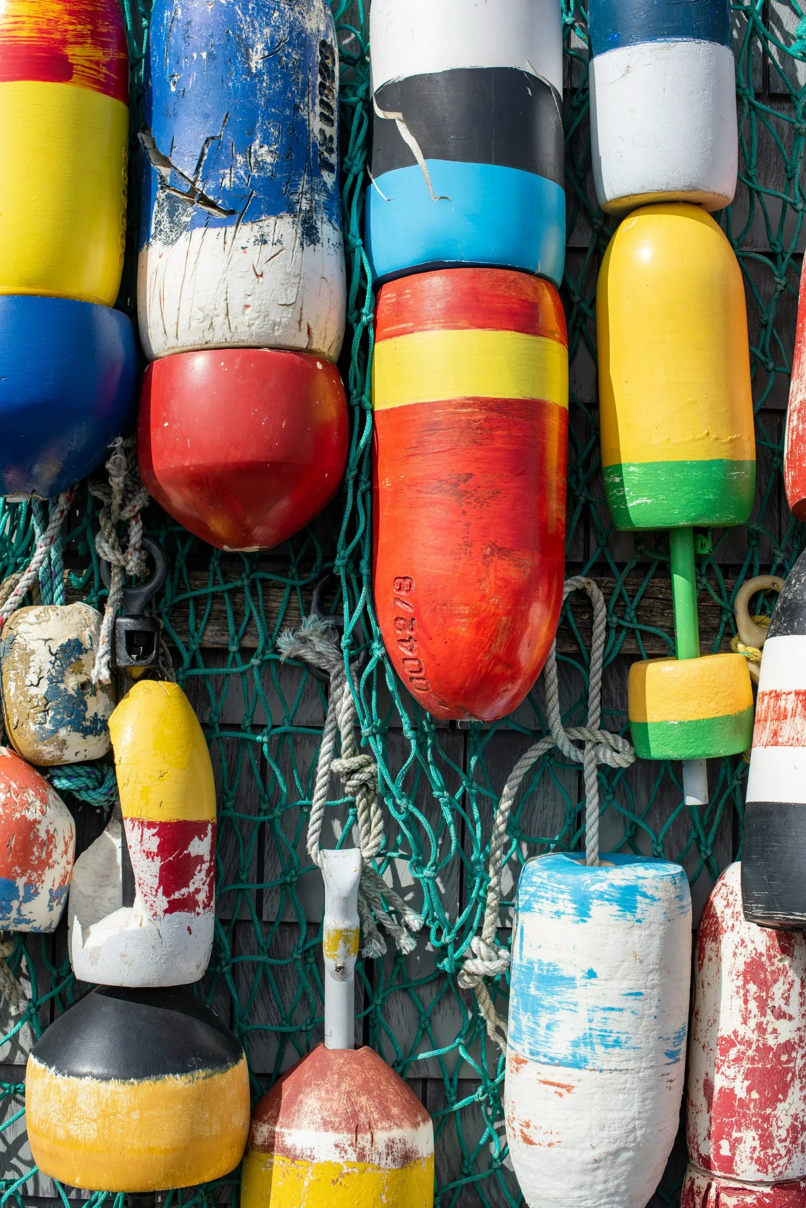 Colorful fishing buoys hanging on a green net.