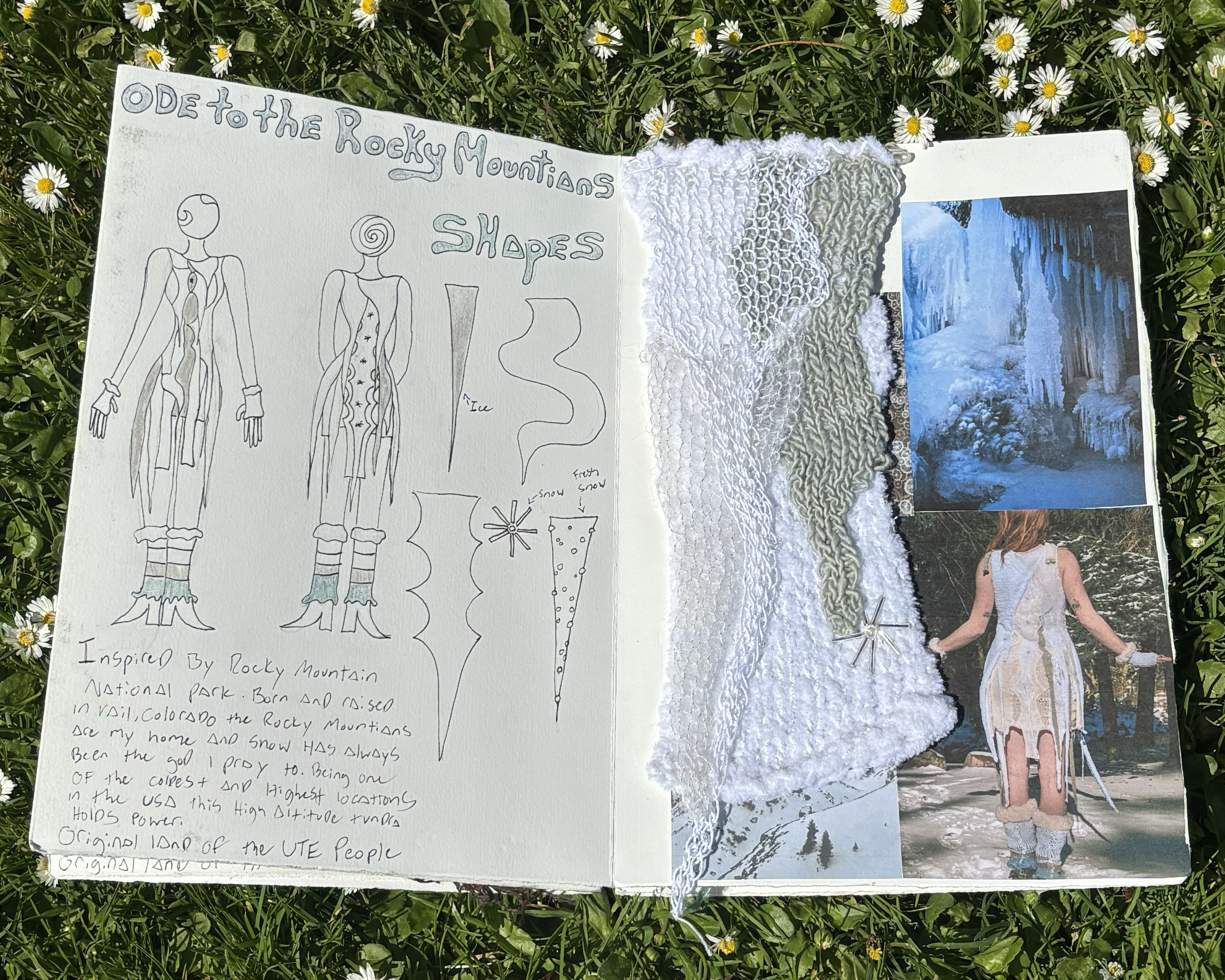 A scrapbook page with sketches of Rocky Mountain shapes, handwritten notes, and pieces of fabric attached, placed on green grass with small white flowers.