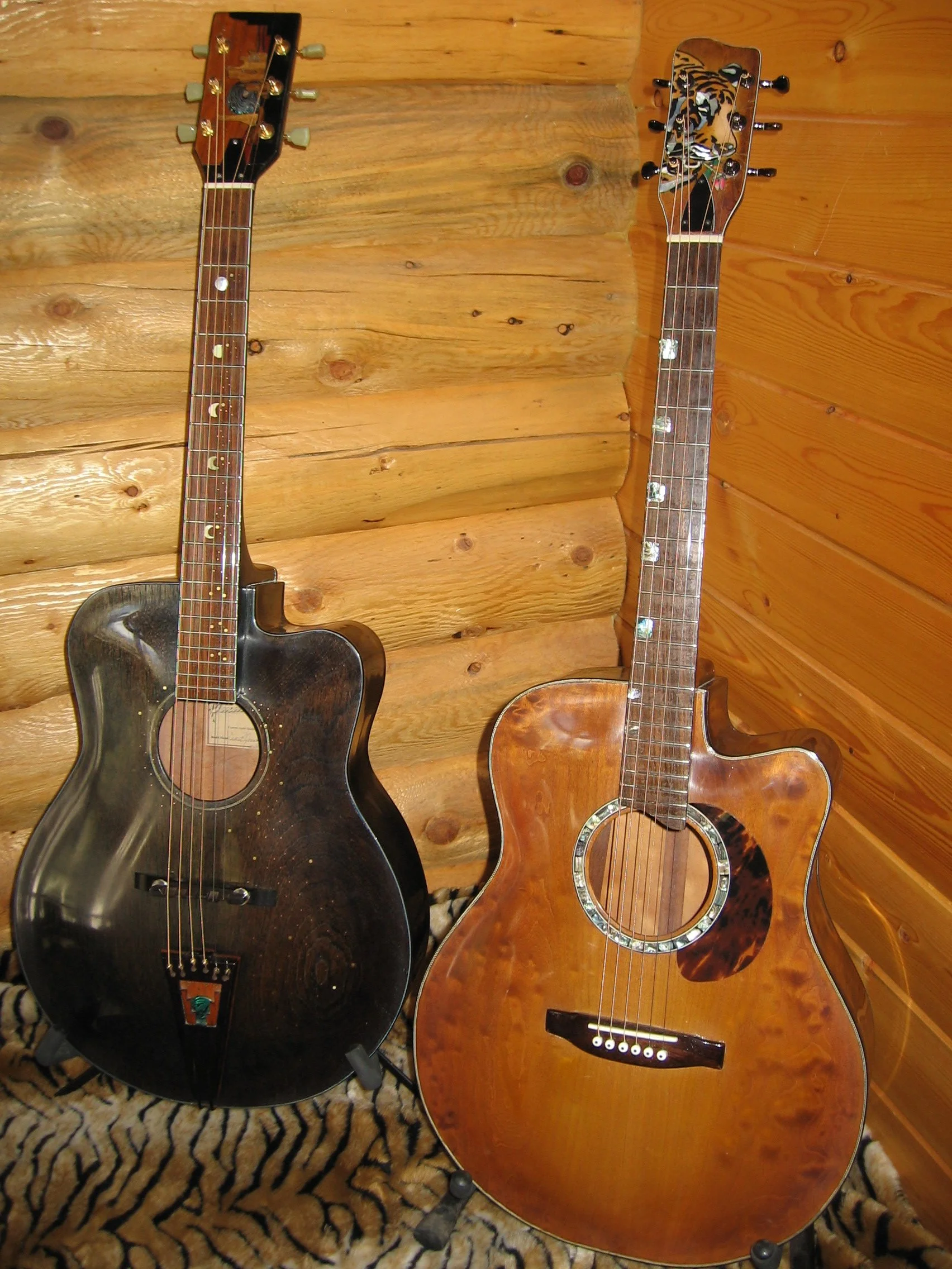 2 acoustic hand carved archtop guitars. Made by Elaine Moulton, luthier at Immortal Guitars. Left one with inlay of desert landscape on tailpiece and headstock, mahogany top, sides, and back. Rosewood fretboard with inlay. Right guitar,AAAA maple, sa